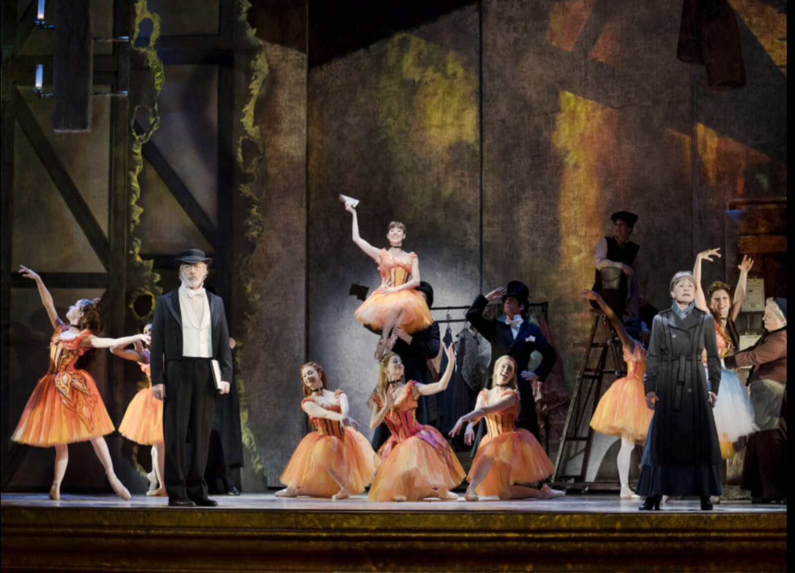 Marie and other ballerinas in butterfly costumes, practicing. Two mentors in black outfits are singing/performing with them. Some ballerinas are trying out costumes at the back.