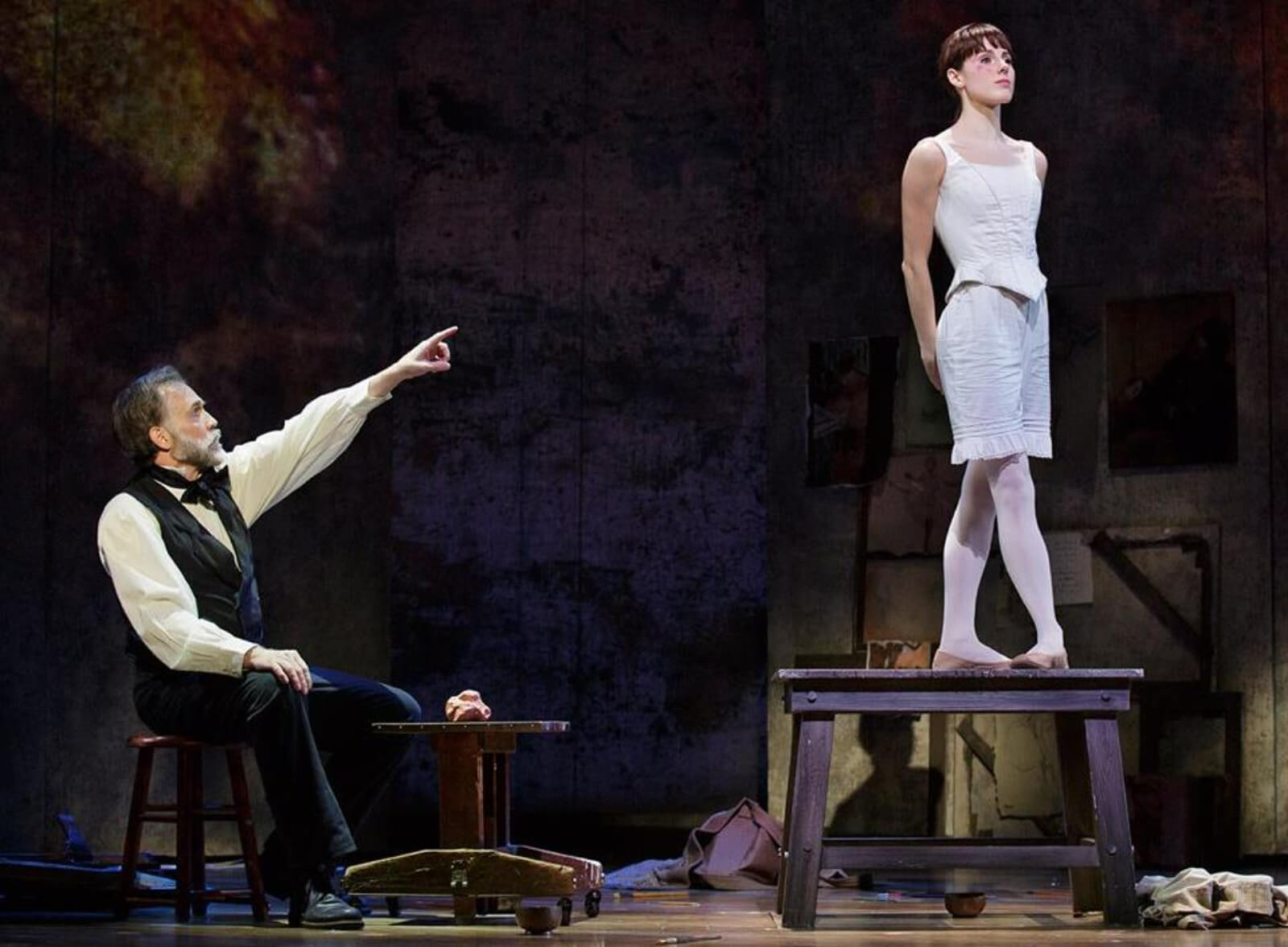 Dega (Boyd Gaines) and Marie (Tiler Peck) in Degas studio in the musical Little Dancer. She is posing in 4th position so Dega can sculpt her.