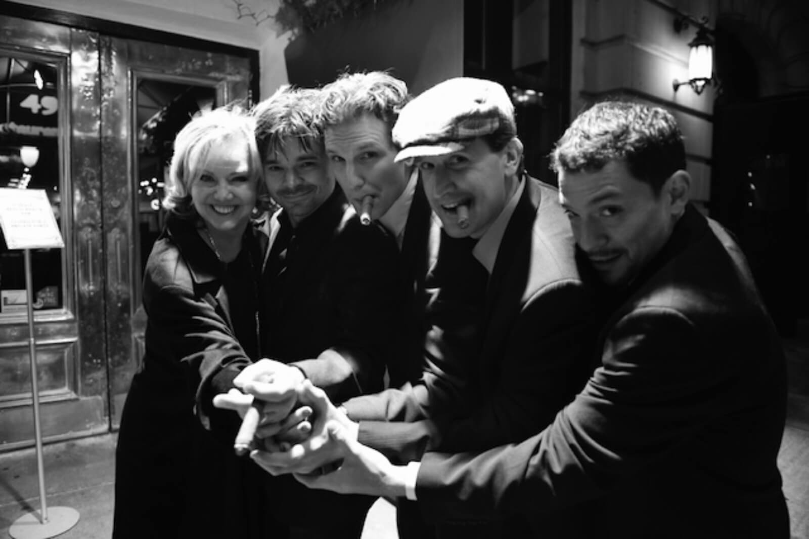 a black and white photo in front of the theater pictured left to right: Susan Stroman, Hunter Foster, Sebastian Arcelus, James Moye, and Miguel Cervantes.