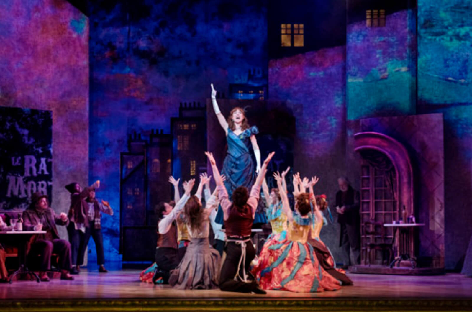 Antoinette (Jenny Powers) singing "Little Opportunities" in Le Rat Mort. She is surrounded by dancers in a circle.