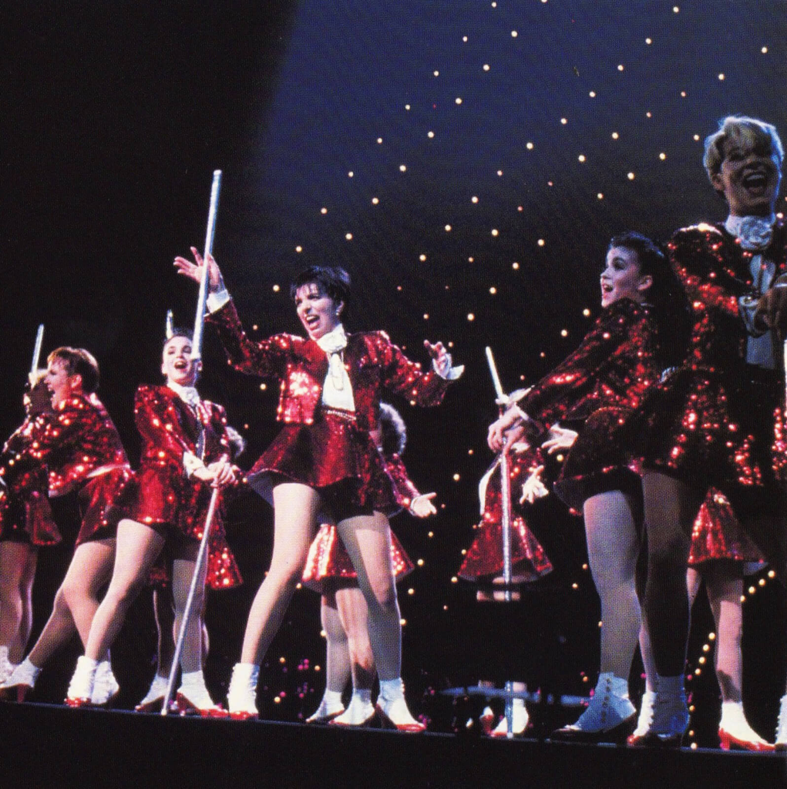 Liza and the Demon Divas. Liza and her dancers all dressed in red sequin outfits and dancing with white canes.