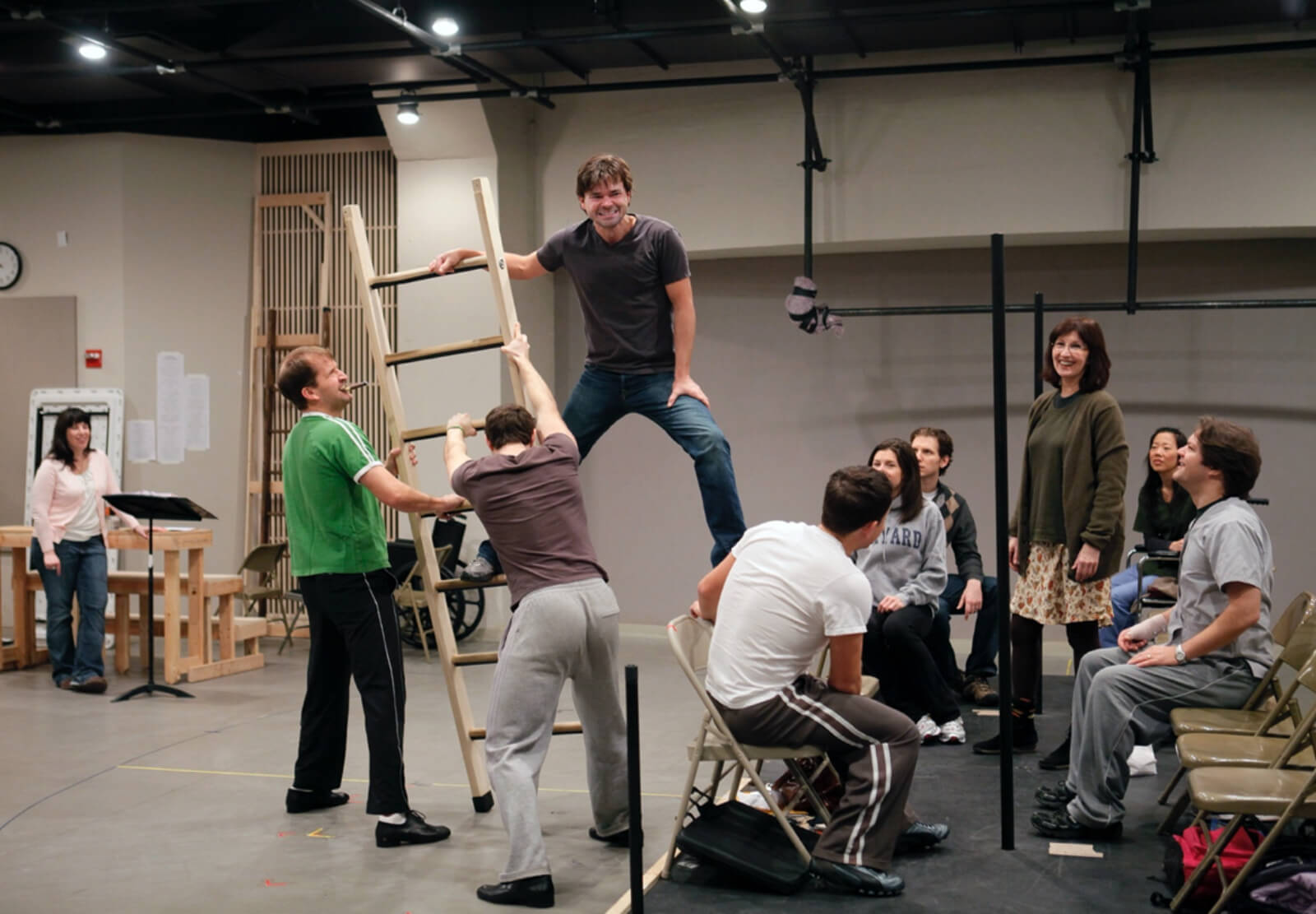 The company of Happiness works through a scene from the show involving a large ladder in a rehearsal studio