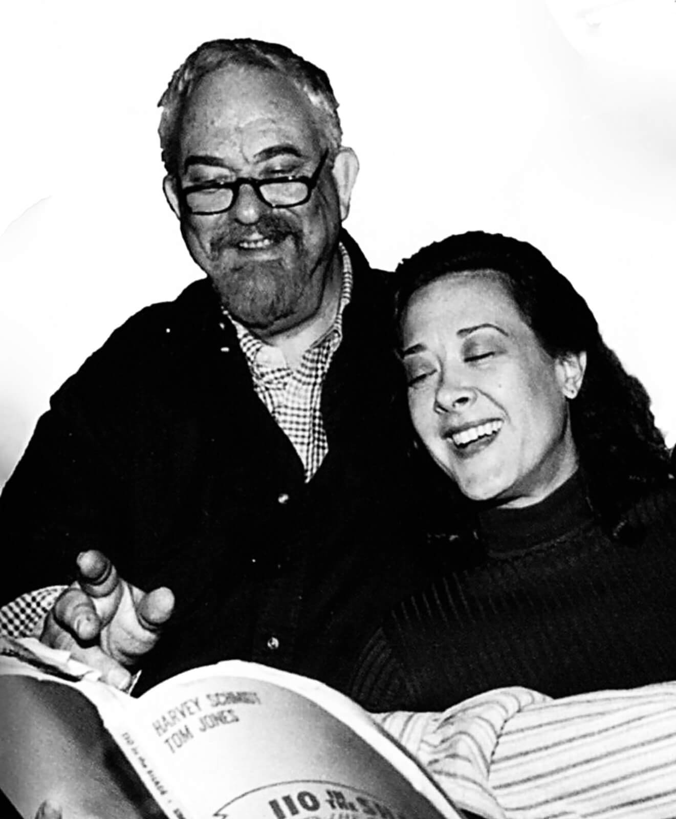 Black and white photo of Harvey Schmidt and Karen Ziemba in rehearsal. Both standing over sheet music, while Karen is singing and Harvey looks on smiling.
