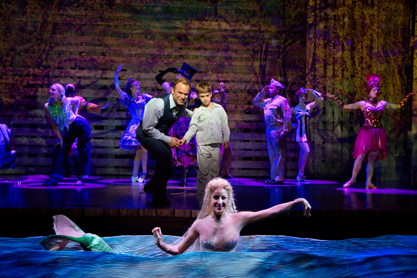 Edward Bloom (Norbert Leo Butz) shows Young Will (Zachary Unger) the mermaid (Sarrah Strimel). The mermaid appears from the water.