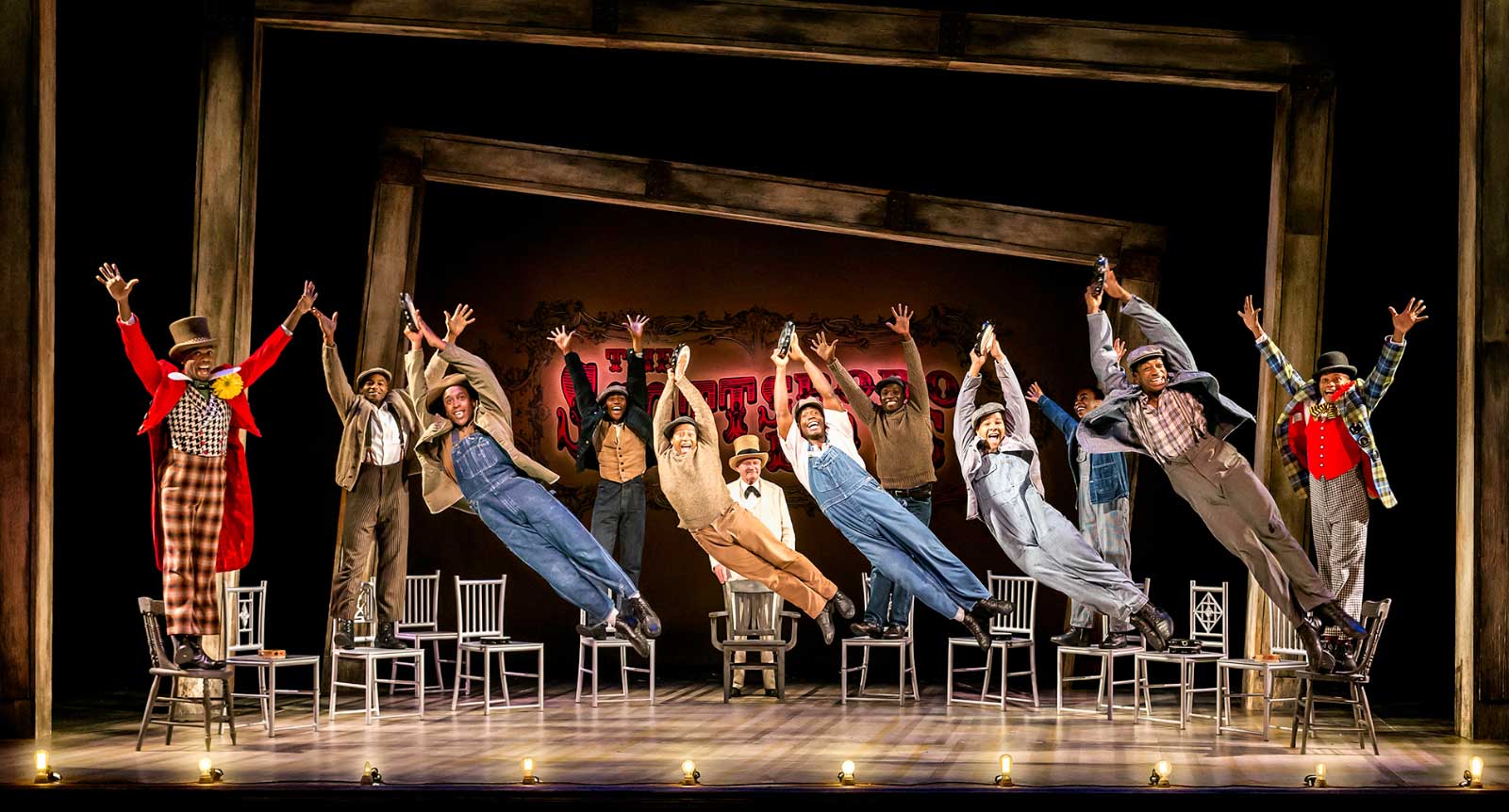 The full company joyously sings "Hey, Hey, Hey, Hey!" They are in the air, doing a big side jump.