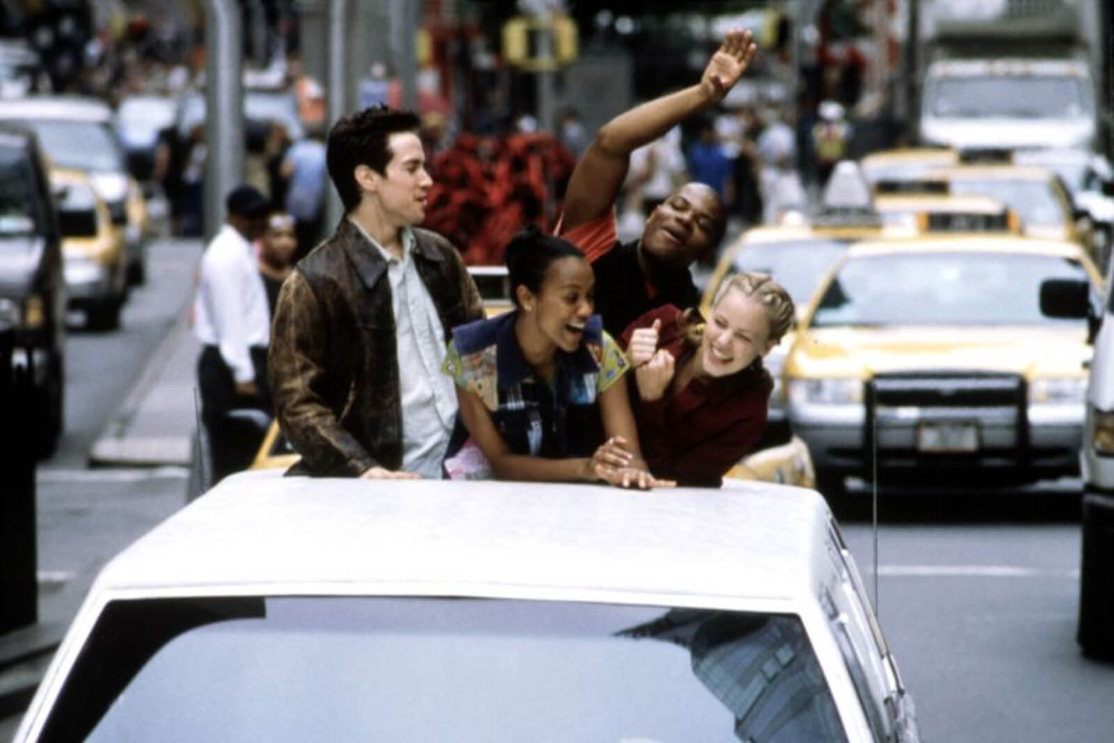 Sascha Radetsky, Zoe Saldana, Shakiem Evans, and Amanda Schull popping out the top of a sun roof in NYC traffic.