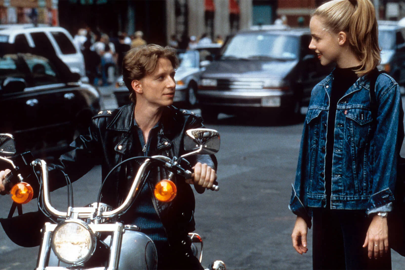 Ethan Stiefel (on motorcycle) speaking to Amanda Schull (standing on street).