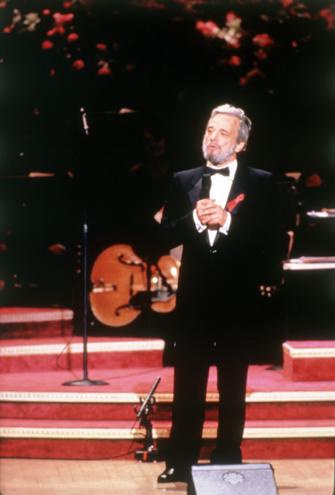 Stephen in a black tuxedo speaks to the audience.