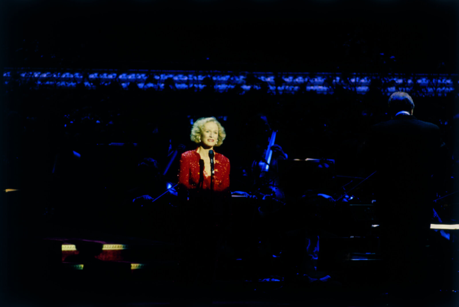 Glenn Close in a spotlight wearing red. 