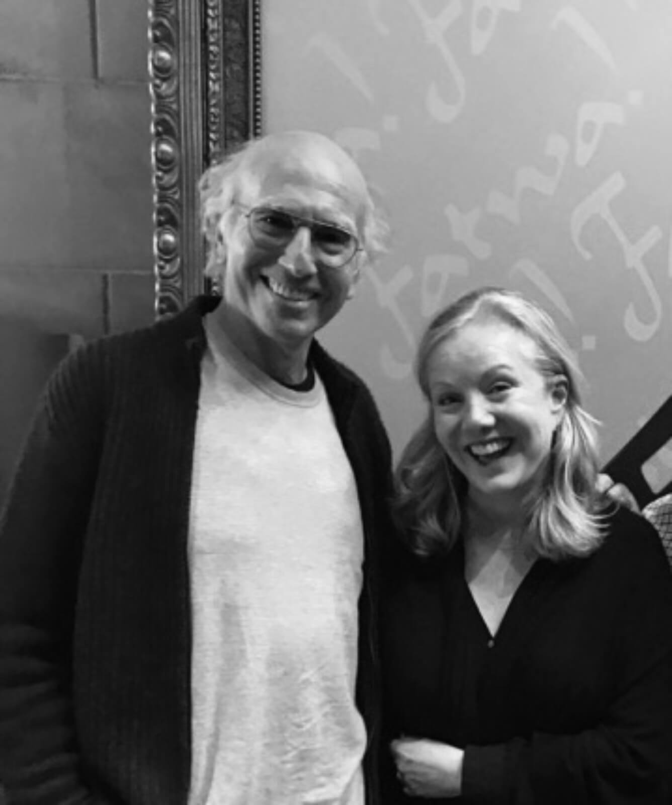 Black and white photo of Larry David and Susan Stroman on the set of HBO’s Curb Your Enthusiasm. Both are smiling.