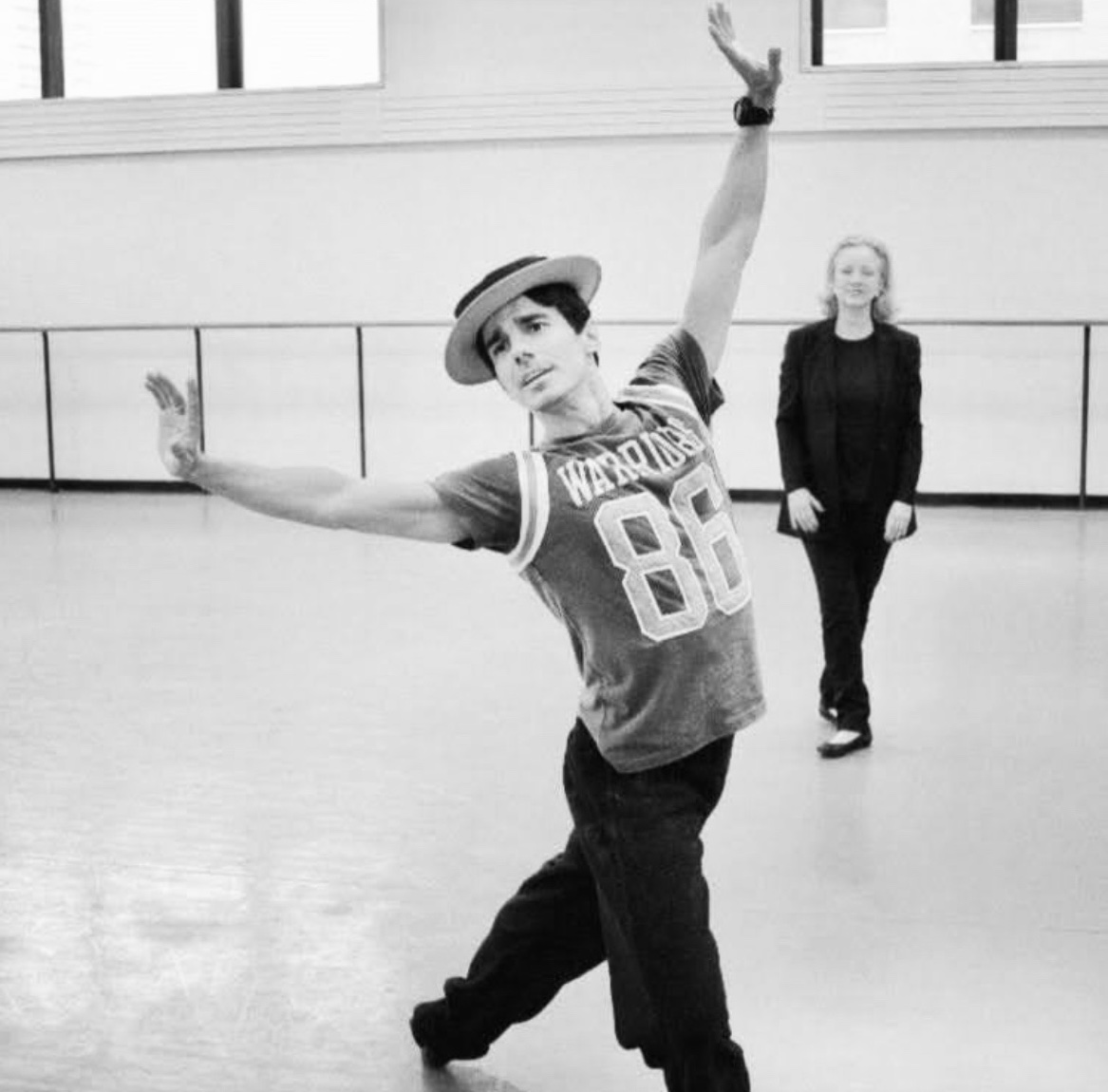 Susan Stroman rehearsing Joaquin De Luz for “Makin’ Whoopee” in the ballet Double Feature. Stroman stands in the back of the dance studio while Joaquin pushes through a lunge in 4th position.