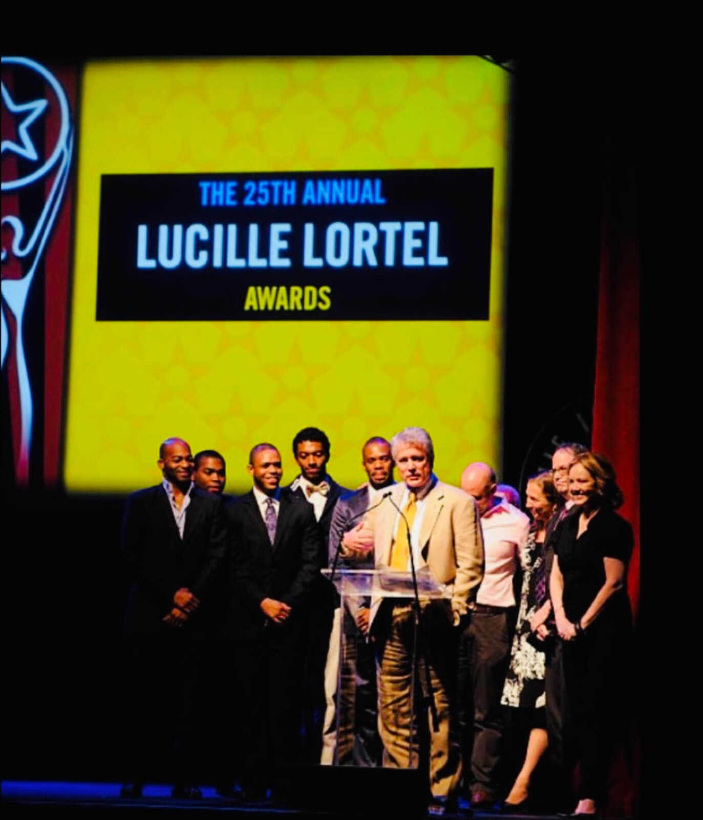 The 2010 Lucille Lortel Awards where The Scottsboro Boys took home the award for Outstanding Musical and Outstanding Choreography. David Thompson is surrounded by the company. Susan Stroman stands smiling to this left.