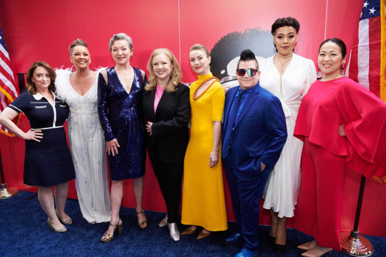 The cast of POTUS with Director, Susan Stroman. They stand on the "pink" carpet dressed in their finest and flanked by American flags.