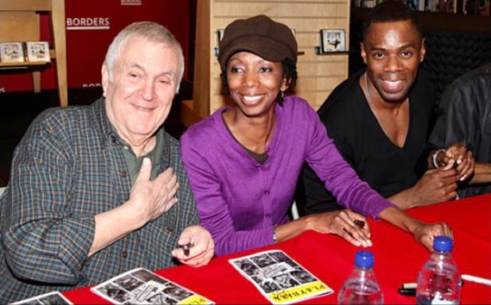 John Kander, Sharon Washington and Colman Domingo signing autographs for The Scottsboro Boys. The yellow Broadway Playbills are on the table - covered in a red tablecloth.