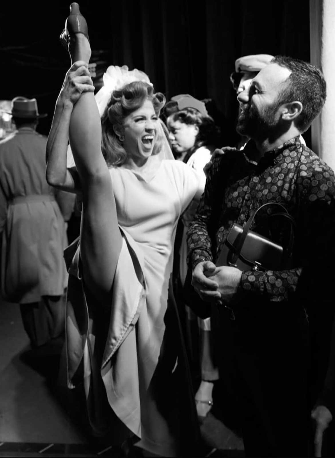 Dancer Ashley Blair Fitzgerald holds her right leg above her head in costume and heels while Stage Manager Johnny Milani looks at her foots and smiles backstage at the St. James Theater.
