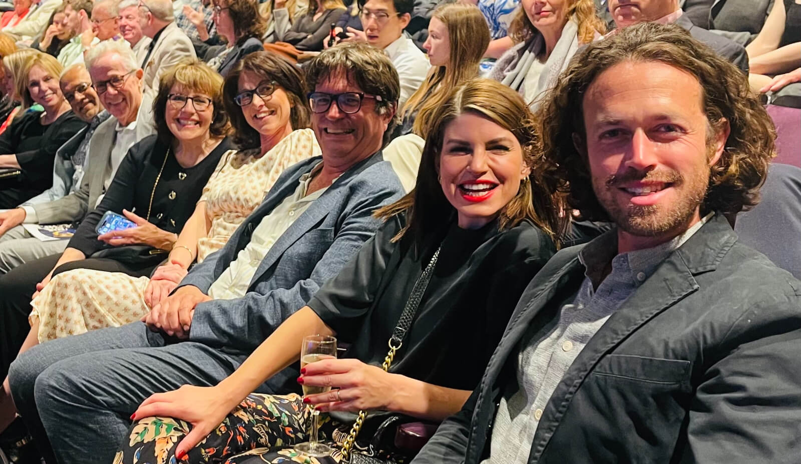 Opening Night Guest (R to L): Ben Ockrent, Jemima Roper, Howard Gooding, Natasha Ockrent, Roz Moore, Bill Hoffman, Andric Bowen, and Jessica Litchner. They are seated in the house of the Gillian Lynne Theatre.