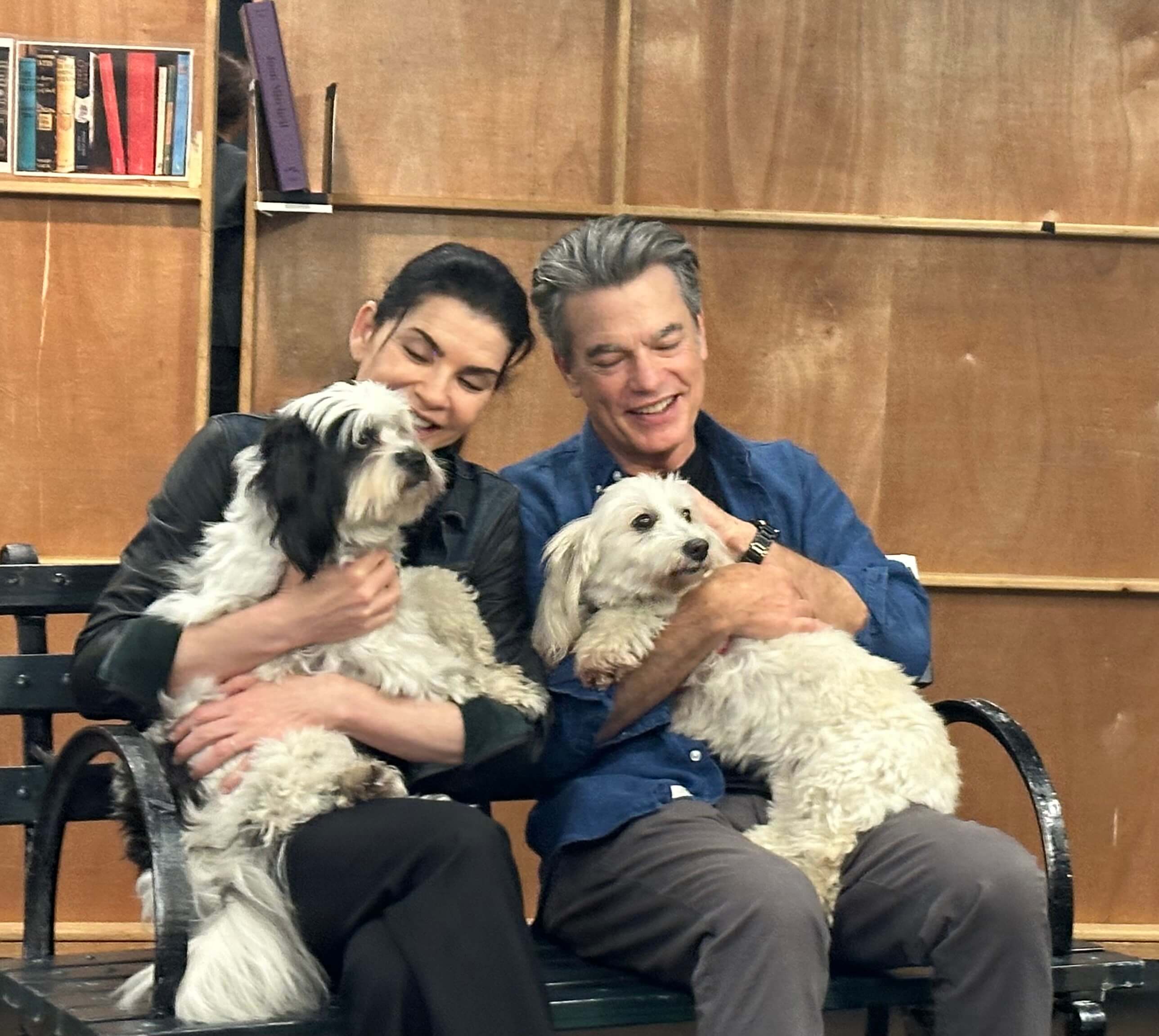 Julianna Margulies (with dog Charlie on her lap) and Peter Gallagher (with dog Dulce in his lap) sit on a bench together while in rehearsal for Left on Tenth. 