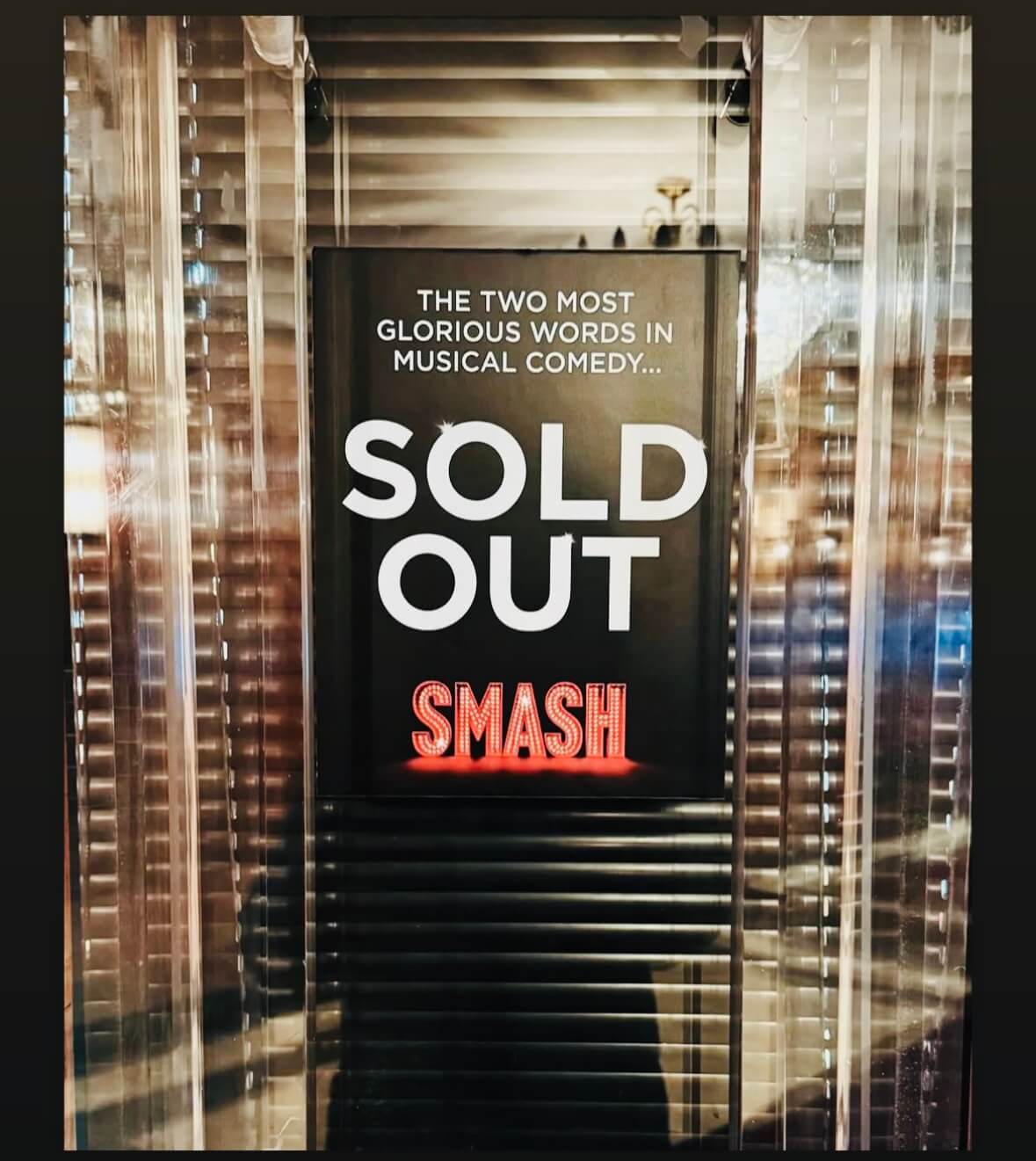 A glass box office display shows the words “The two most glorious words in musical comedy… SOLD OUT” with SMASH glowing in red lights below.
