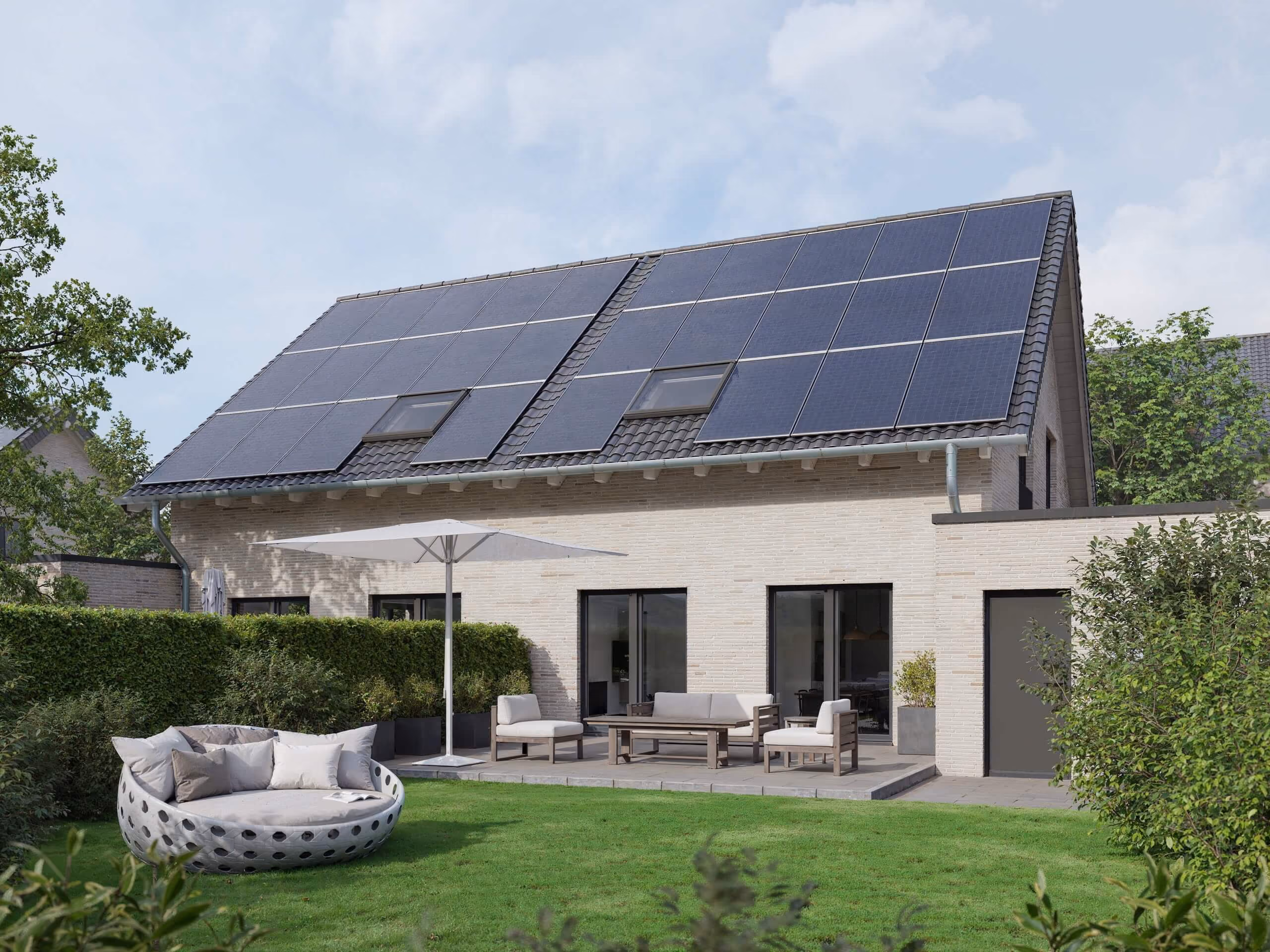 Modern house with solar panels on roof, patio furniture, umbrella, and green garden lawn.