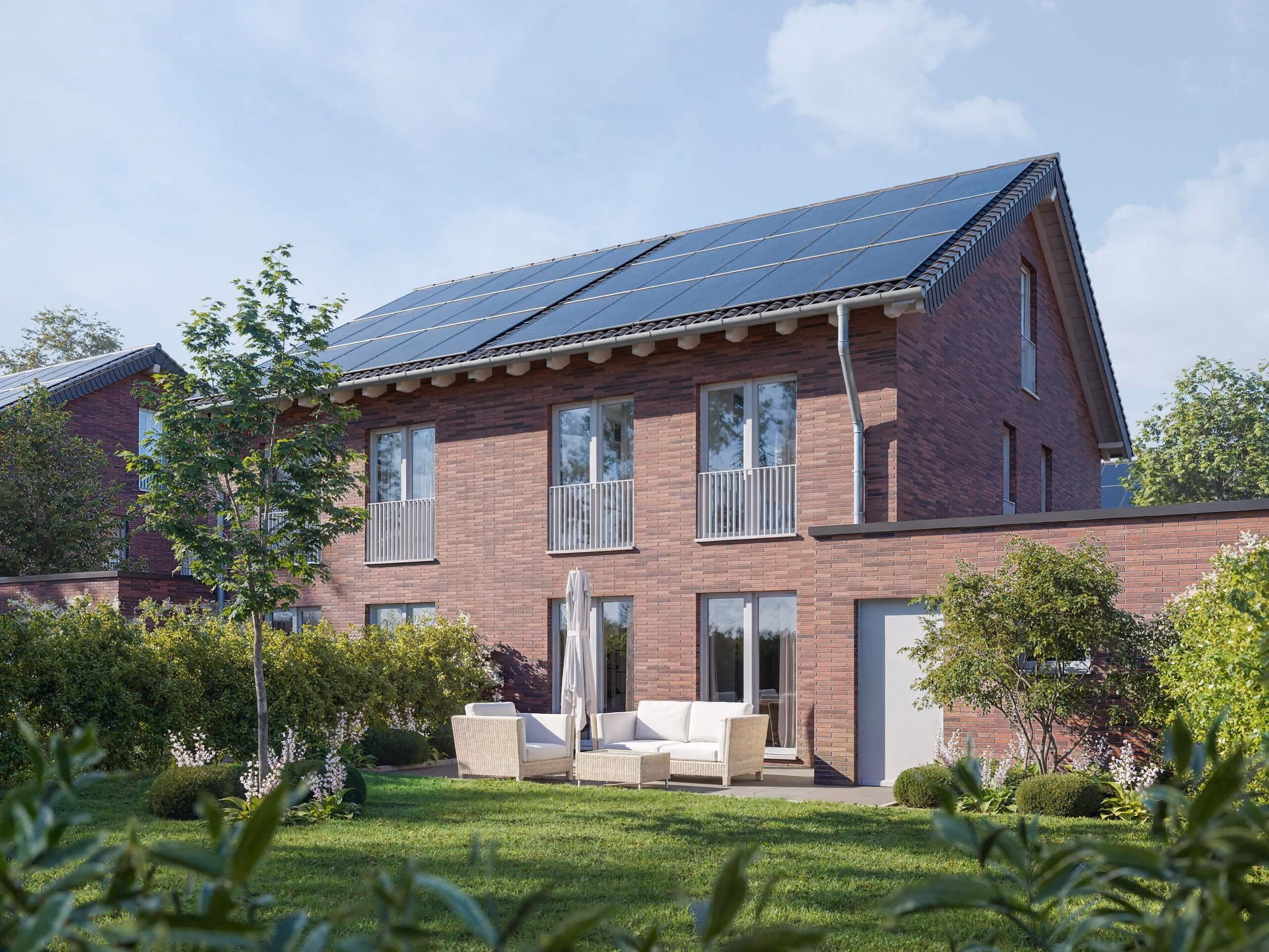 Modernes Backsteinhaus mit Solarpaneelen auf dem Dach und Gartenmöbeln auf der Terrasse.
