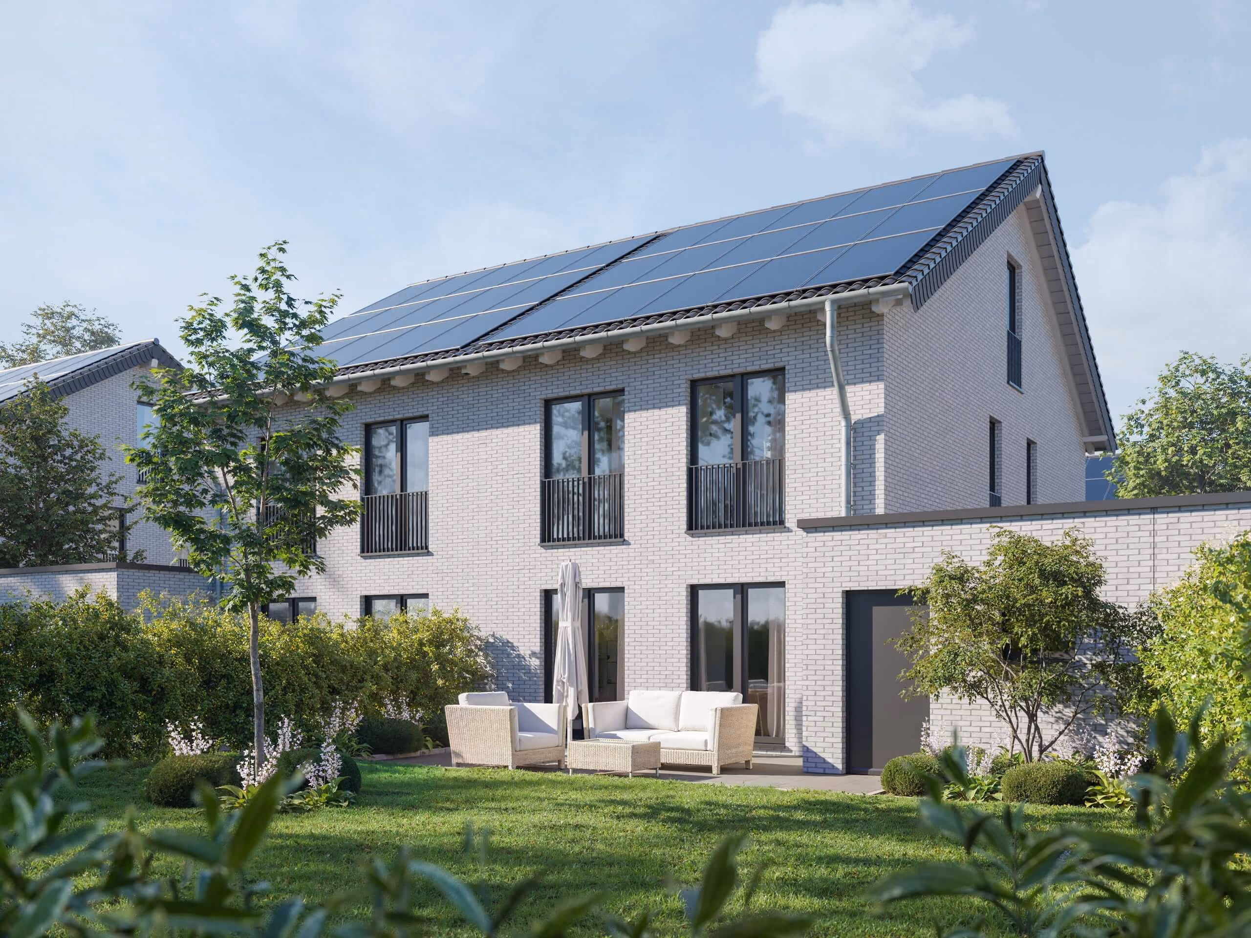 Modernes Haus mit Solarzellen auf dem Dach und Garten mit Sitzbereich und grüner Rasenfläche.