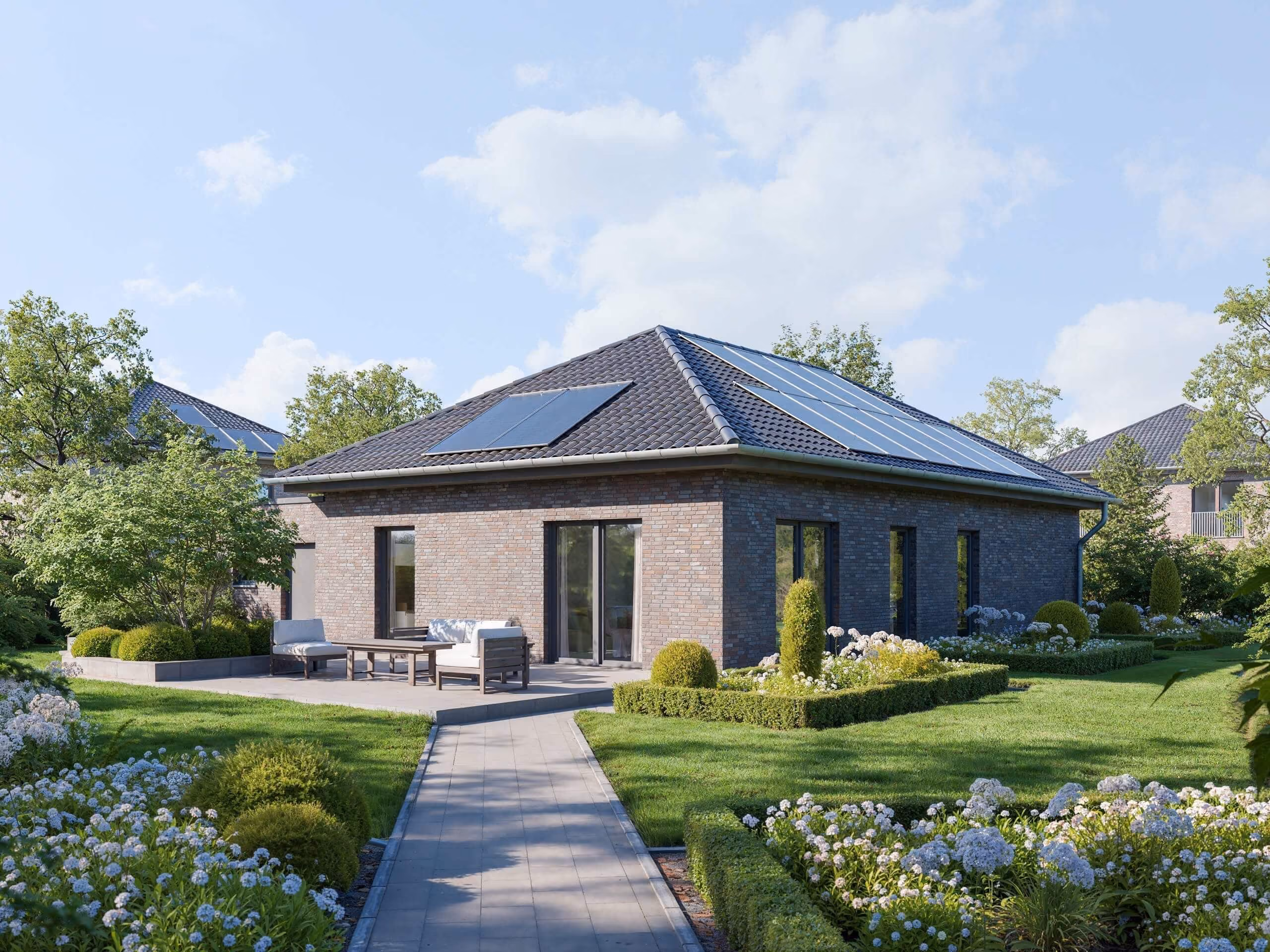 Modernes Einfamilienhaus mit Solarmodulen auf dem Dach und gepflegtem Garten mit Terrasse und blühenden Pflanzen.