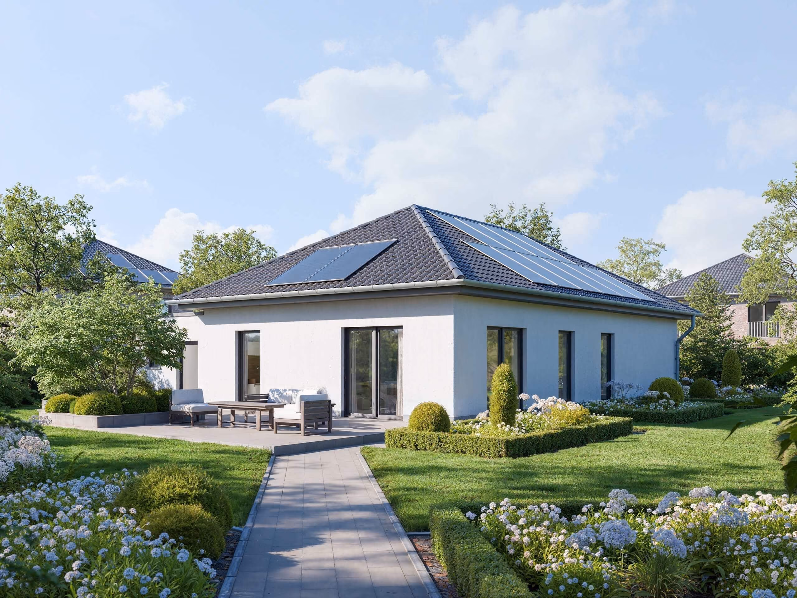 Modernes weißes Einfamilienhaus mit Solarpanels auf dem Dach und gepflegtem Garten mit Wegen und Blumen.