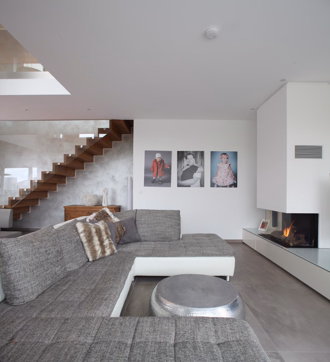 Wohnzimmer mit Kamin, Sofa und Treppe im Hintergrund