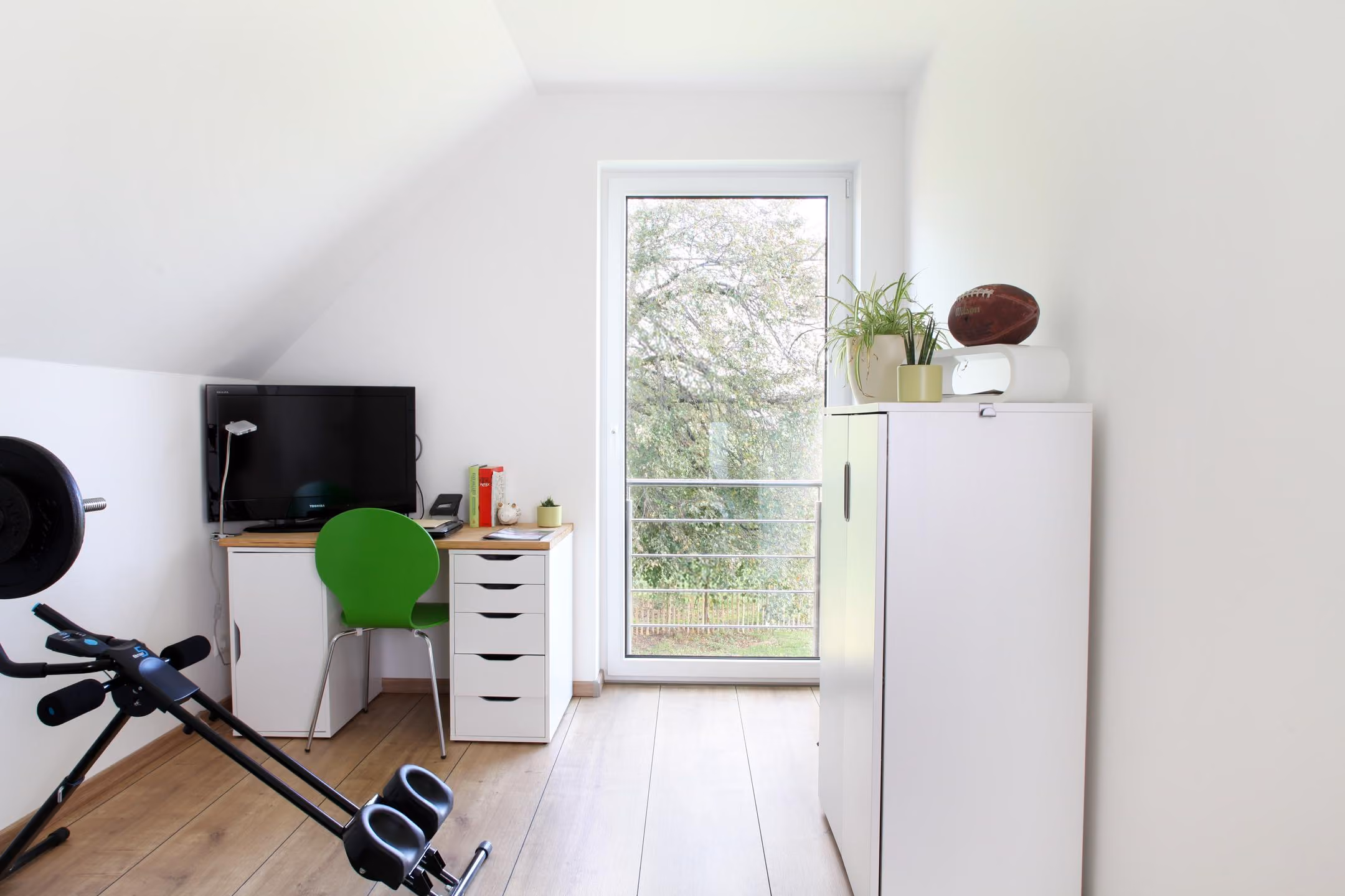 Zimmer im Dachgeschoss mit Schreibtisch und Regal