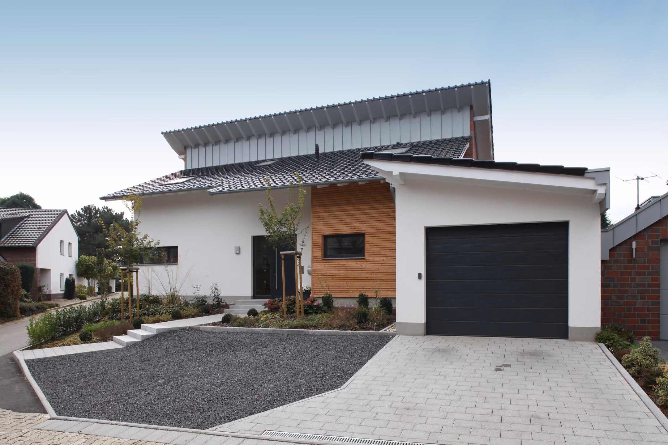 Einfamilienhaus in Wegberg mit weißer Putzfassade, Holzverkleidung und Garage