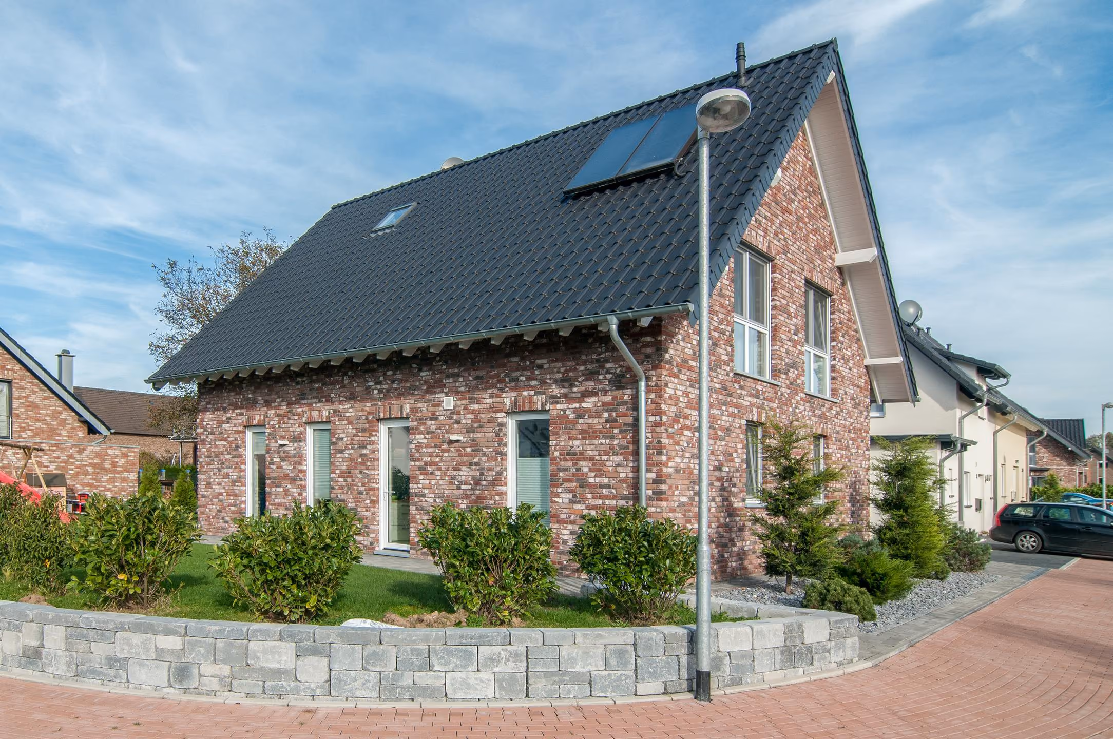 Straßenansicht des Klinkerhauses mit Solarmodulen auf dem Dach