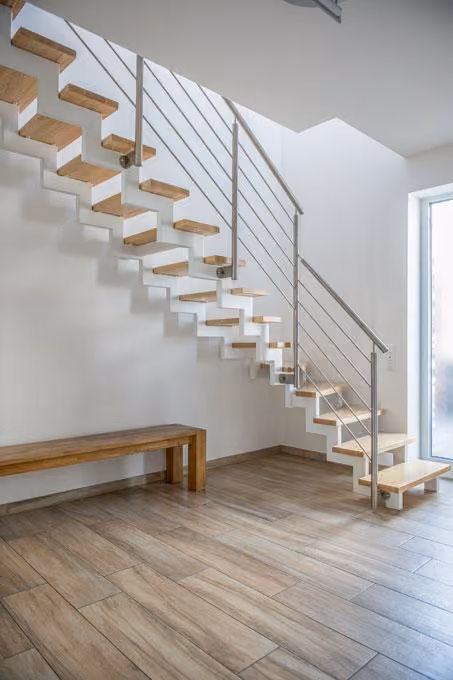 Treppenhaus mit offener Holztreppe und Sitzbank
