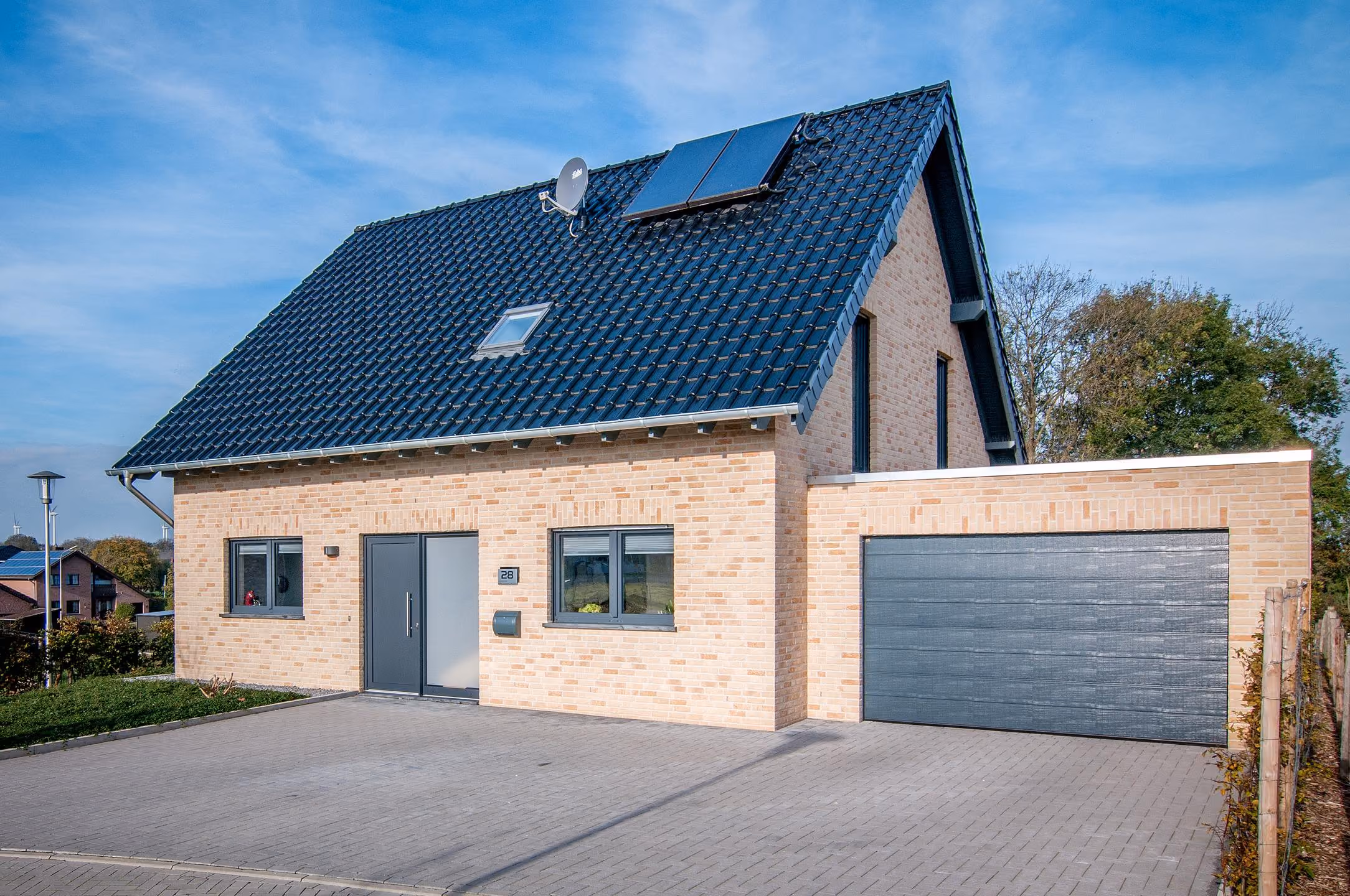 Einfamilienhaus in Bocket mit hellem Klinker, dunklem Dach und Garage