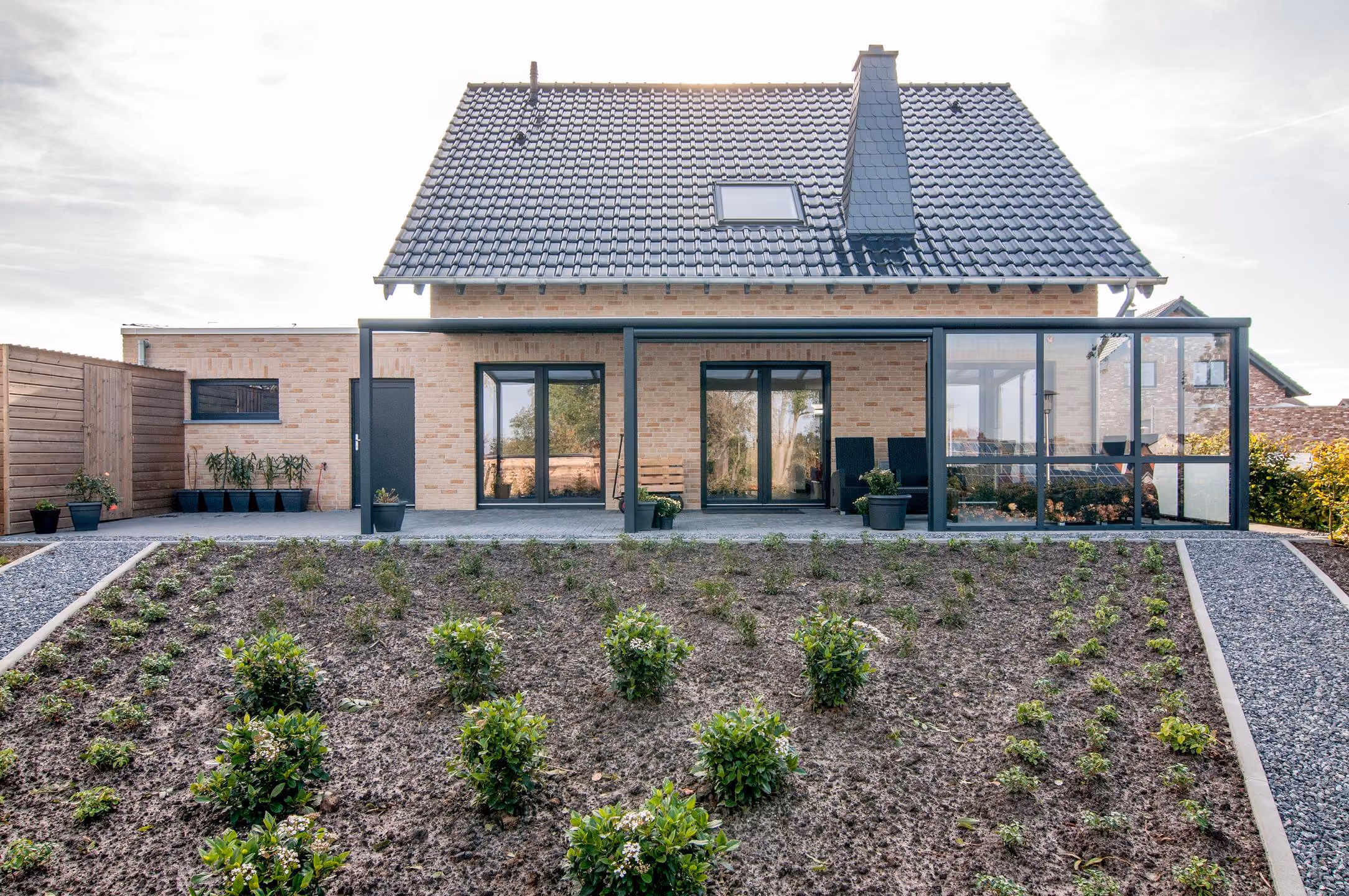 Gartenansicht mit Terassenüberdachung und Blumenbeet