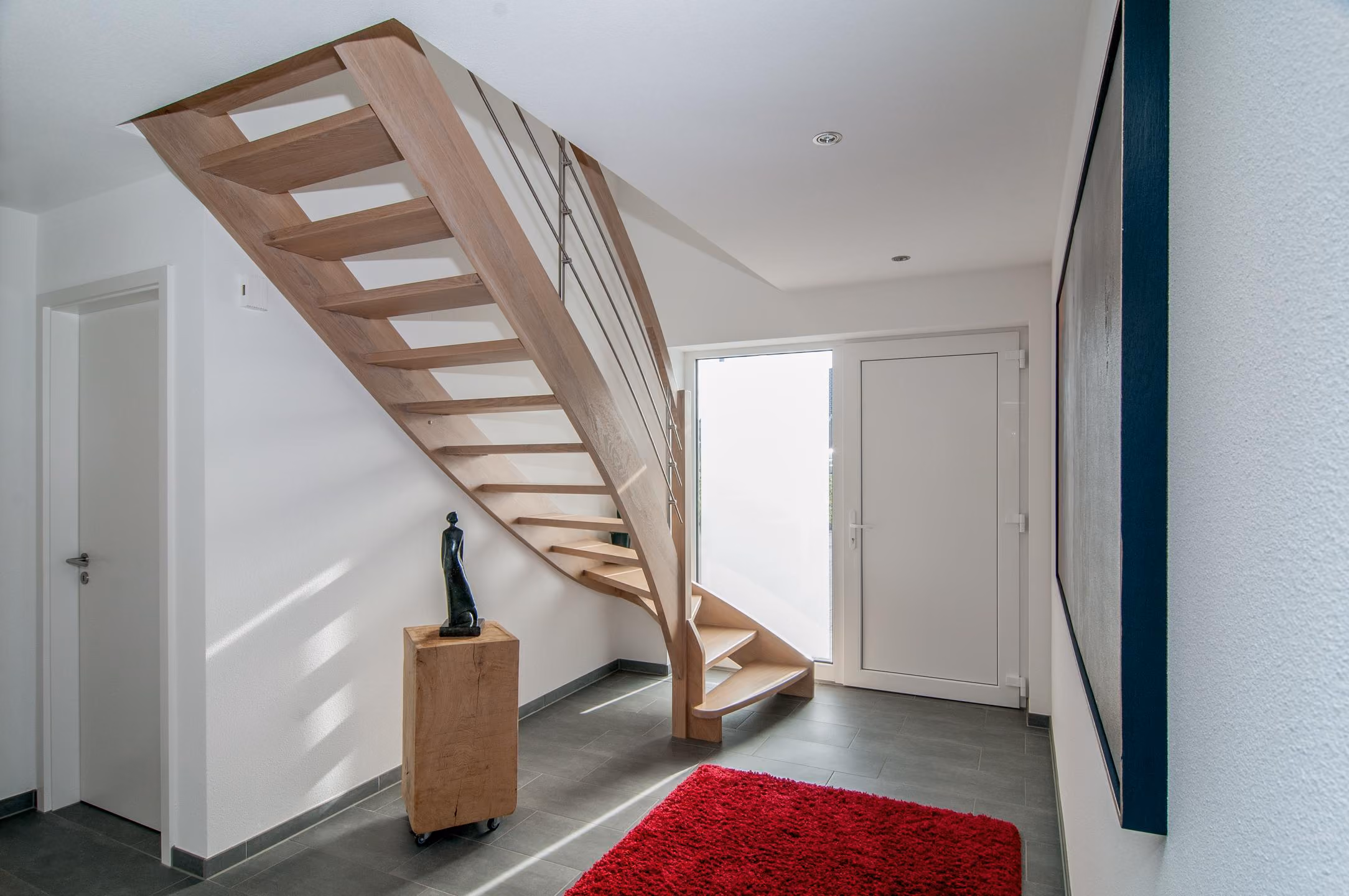 Eingangsdiele mit offener Holztreppe und rotem Teppich