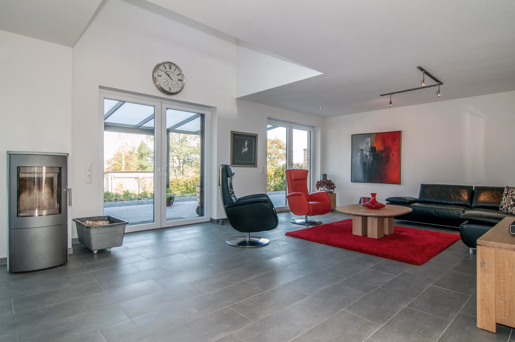 Wohnzimmer mit Sessel, roten Farbakzenten und Fensterfront