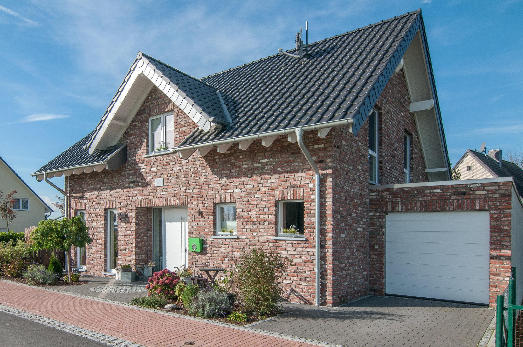 Hausansicht mit Garage und gepflasterter Einfahrt