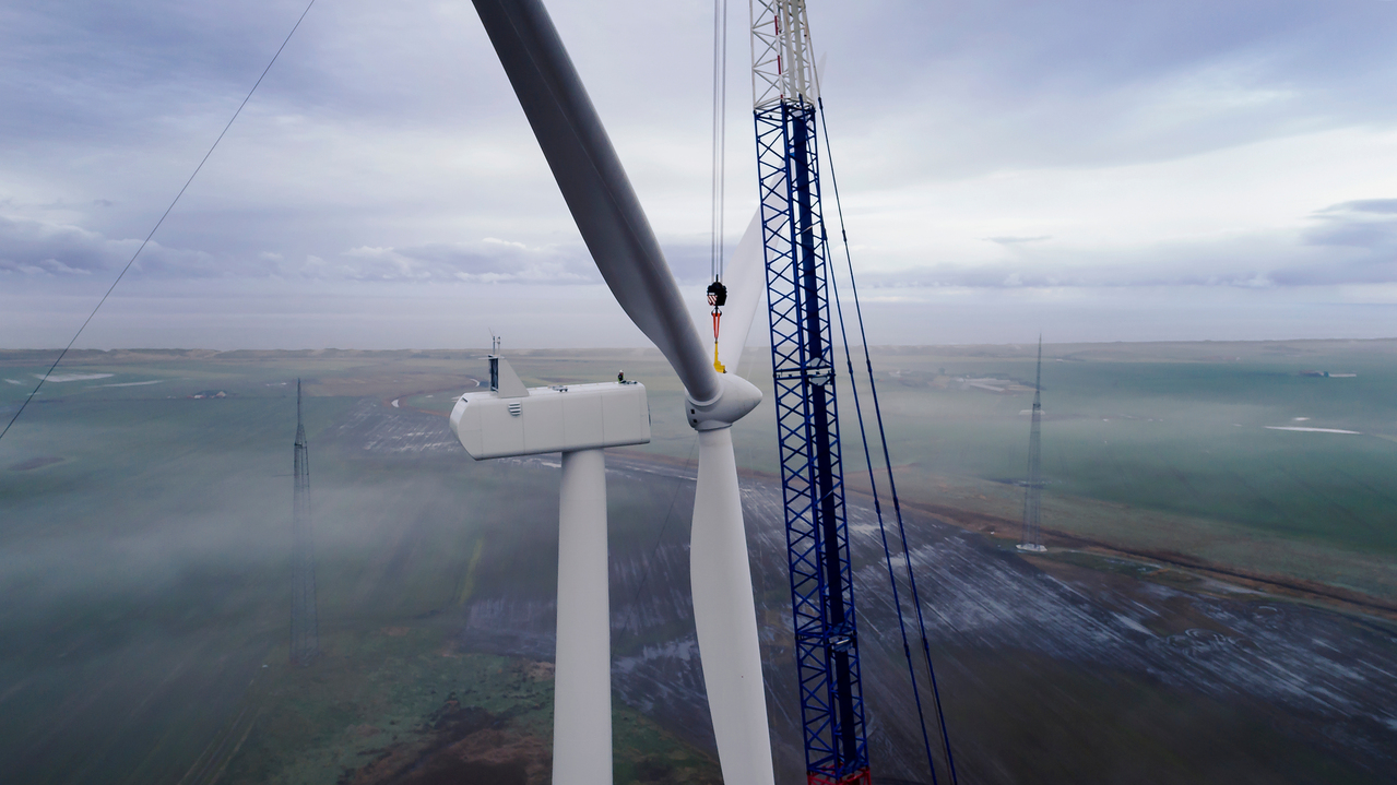 A crane attaching the blades of a wind turbine to the turbine base