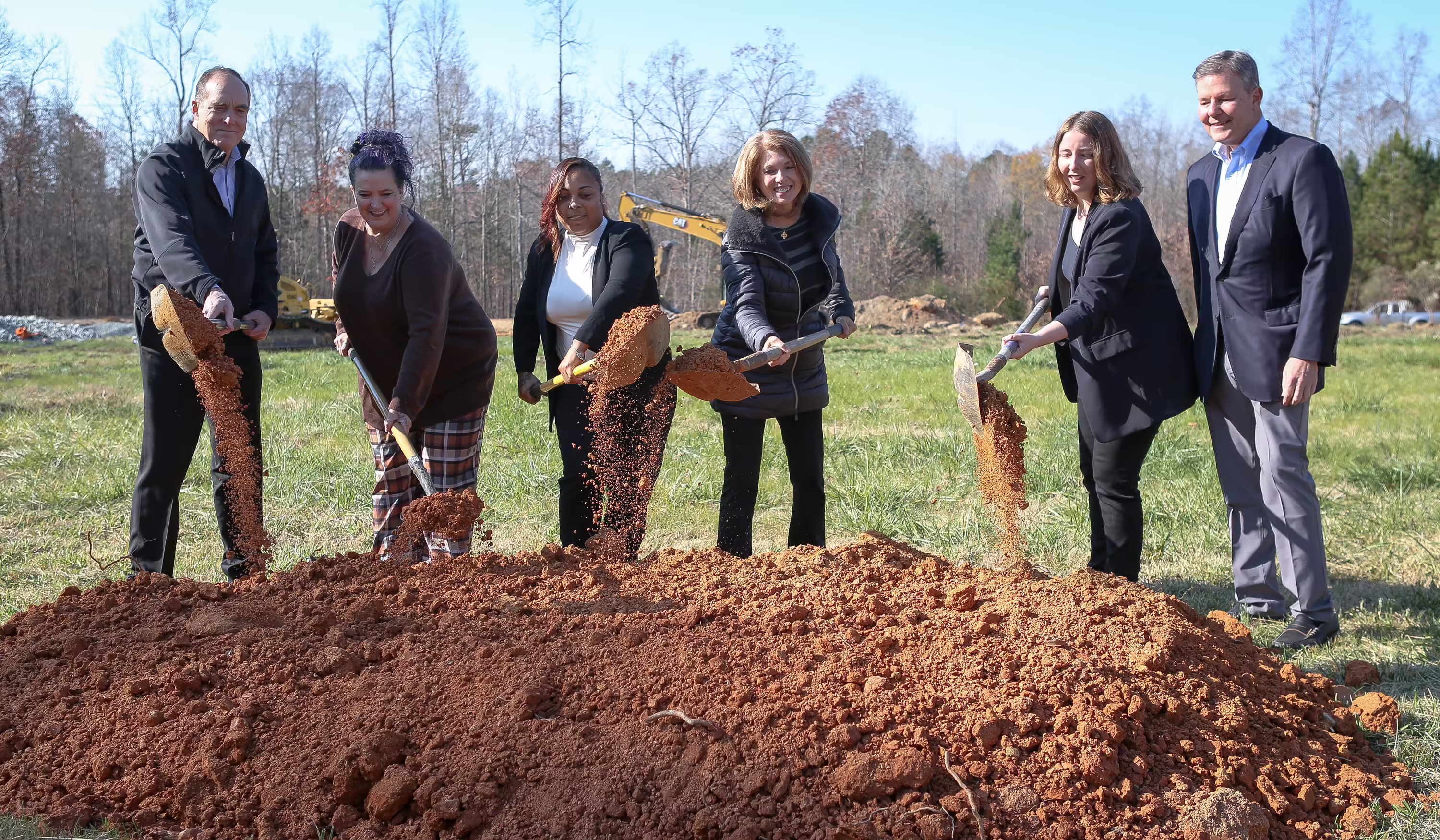 Staff, alumni and supporters turning soil at the tiny home community groundbreaking