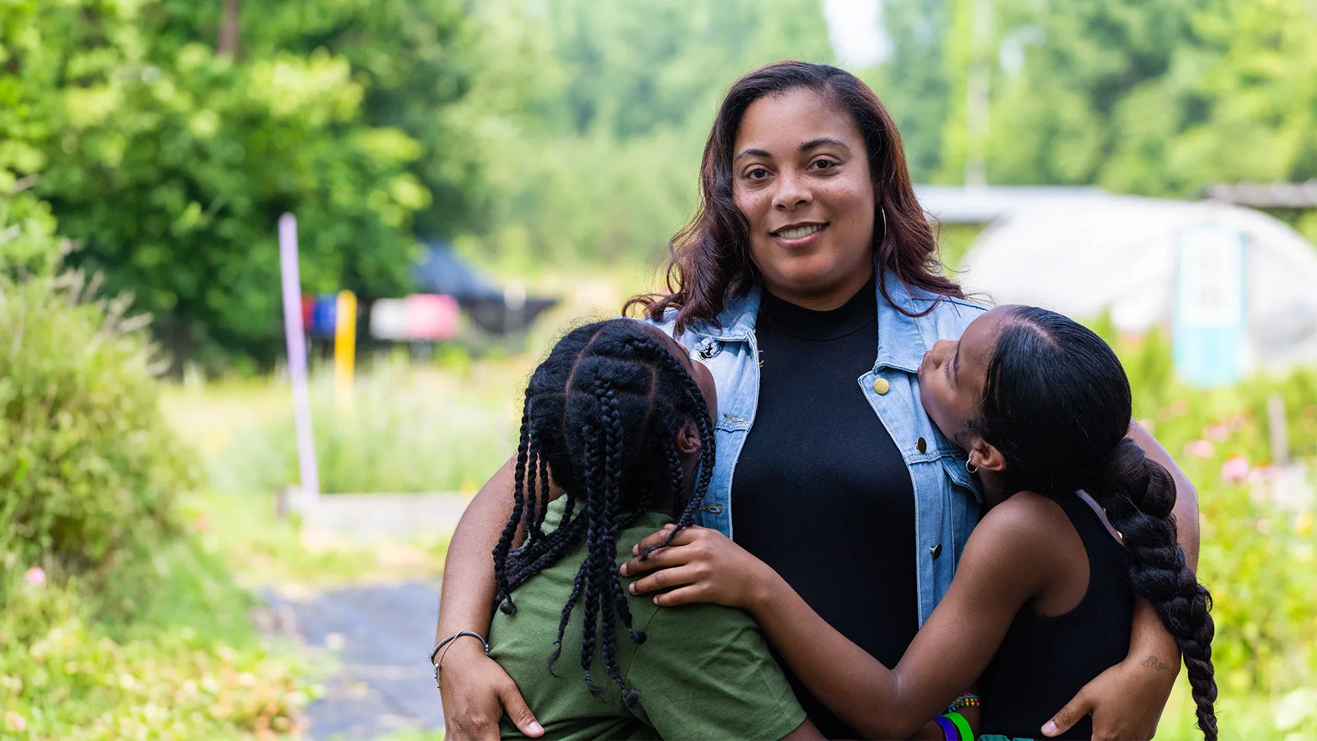 A woman standing with two children on the farm