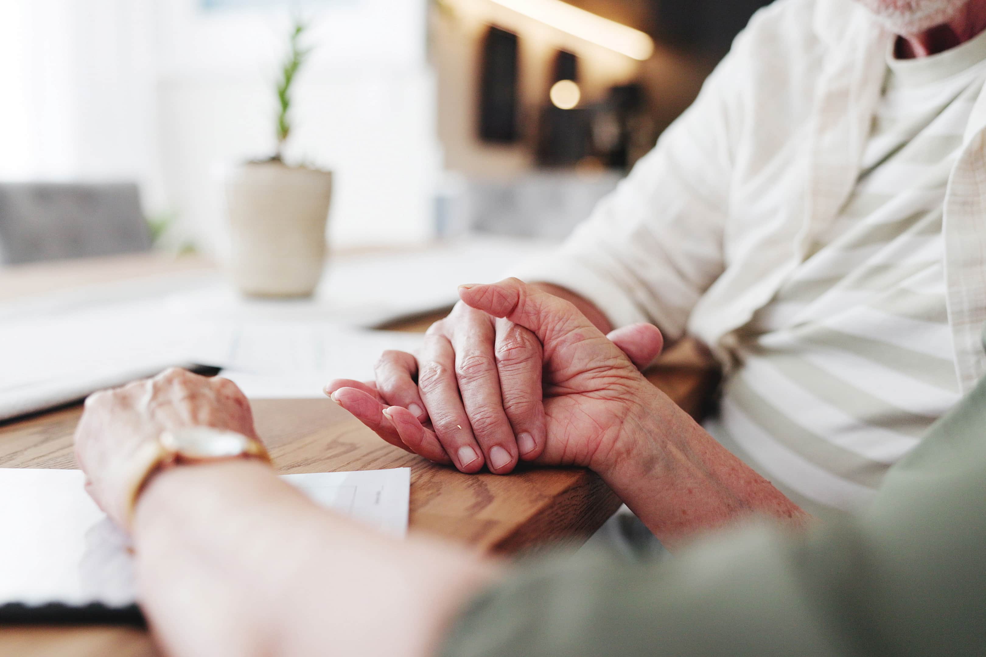 Elderly couple holding hands at office desk