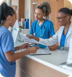 Two nurses and a doctor discussing patient documents at a hospital reception desk.