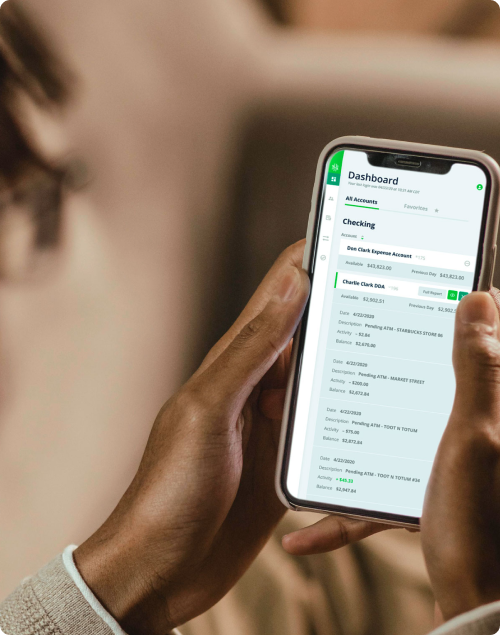 Person holding smartphone showing a banking app dashboard with checking account details.