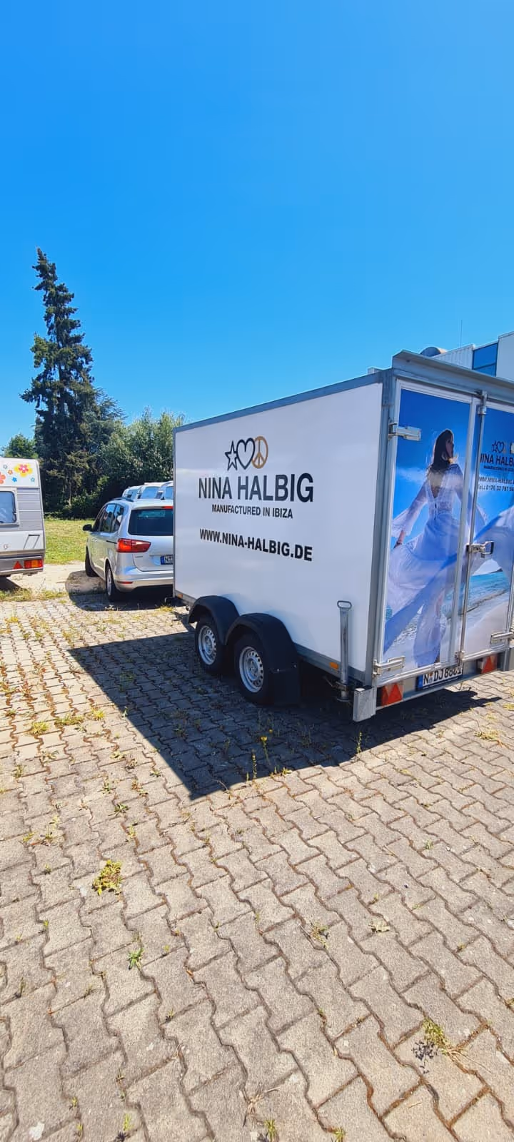 Anhänger mit Werbung für Nina Halbig, hergestellt in Ibiza, mit Websiteadresse und Bild einer Frau am Strand.