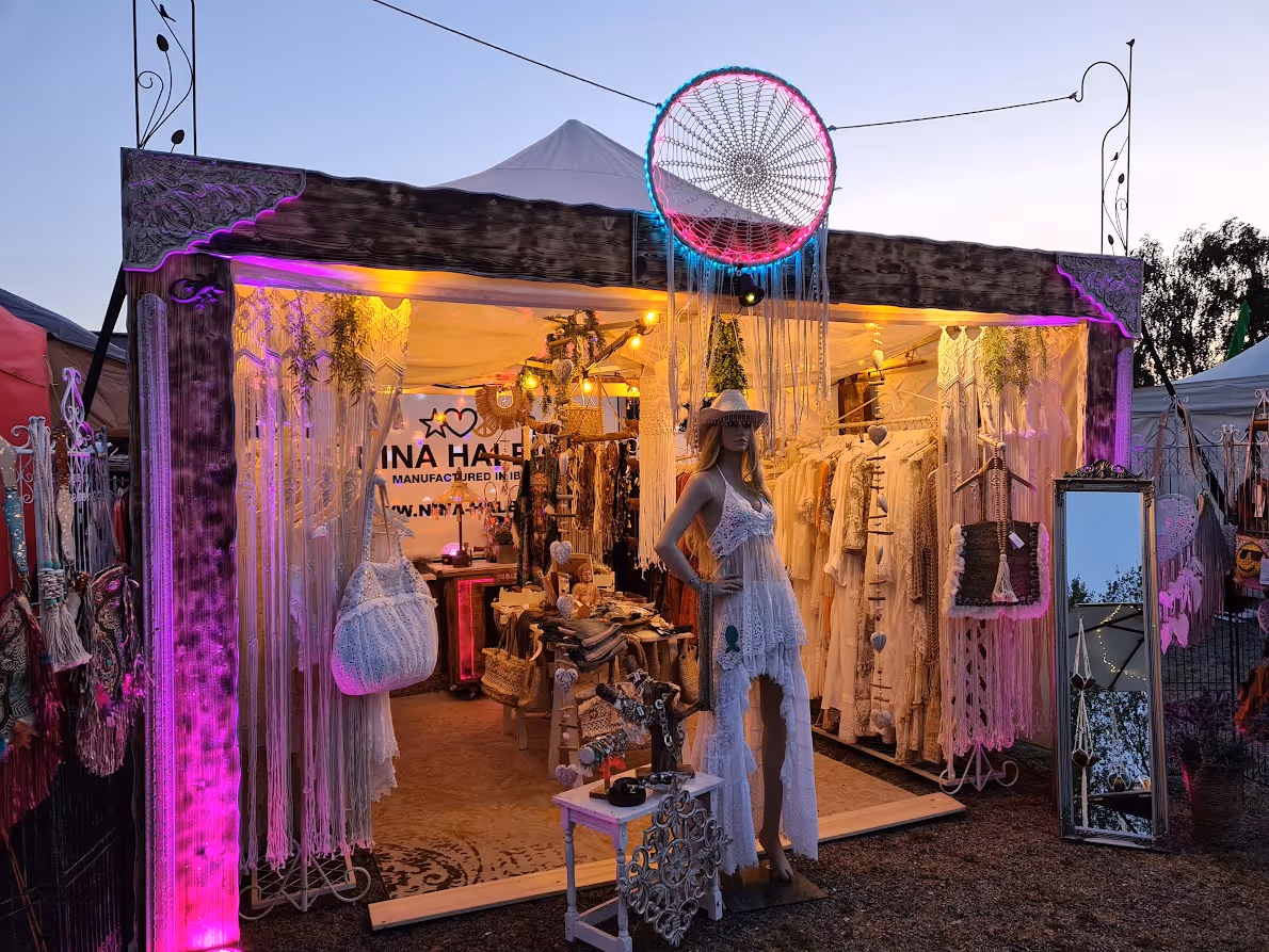 Abendmarktstand mit Boho-Bekleidung, Makramee-Dekor und einem Schaufensterpuppe in weißem Spitzenkleid.