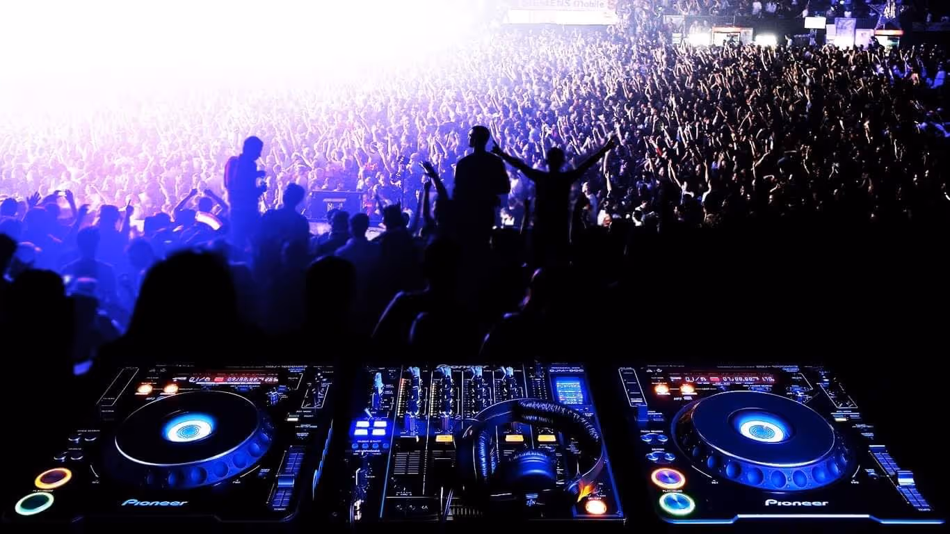 DJ-Pult mit Pioneer Ausrüstung vor einer jubelnden Menschenmenge bei einem Konzert.