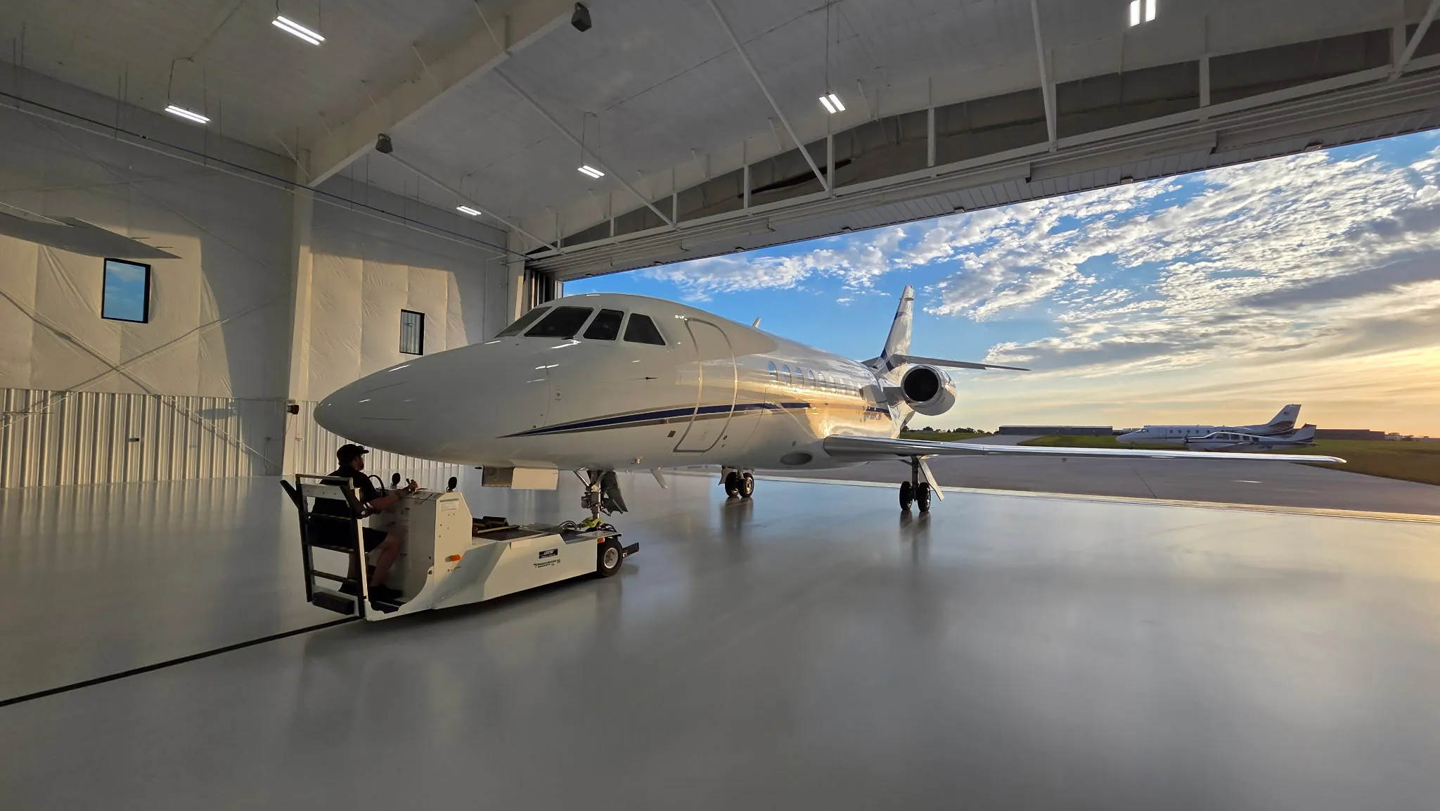 Private jet parked on a freshly coated high-gloss gray epoxy hangar floor at sunset, installed by GroCo