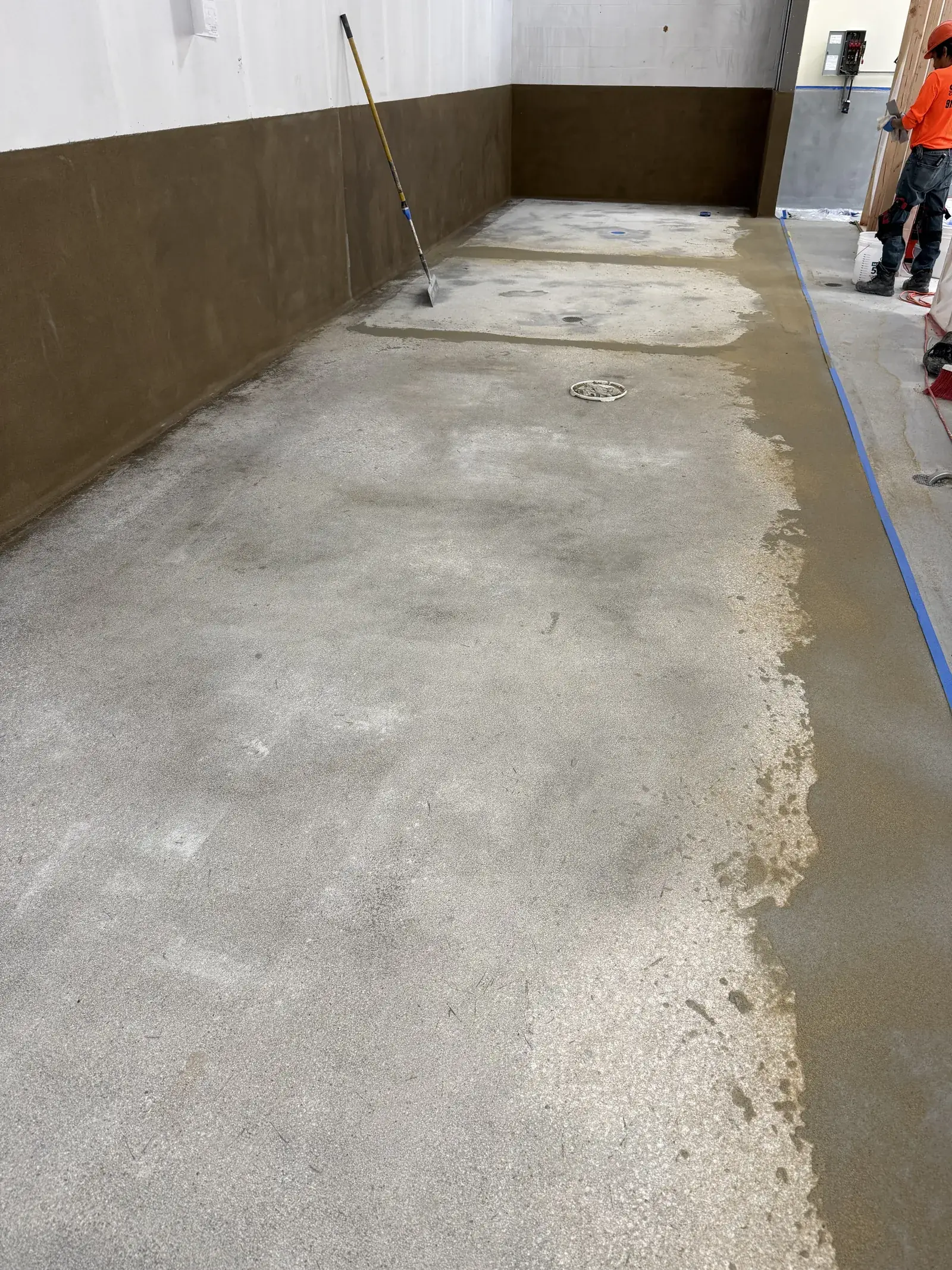 Diamond-ground concrete floor prepped for coating with crew at the far wall