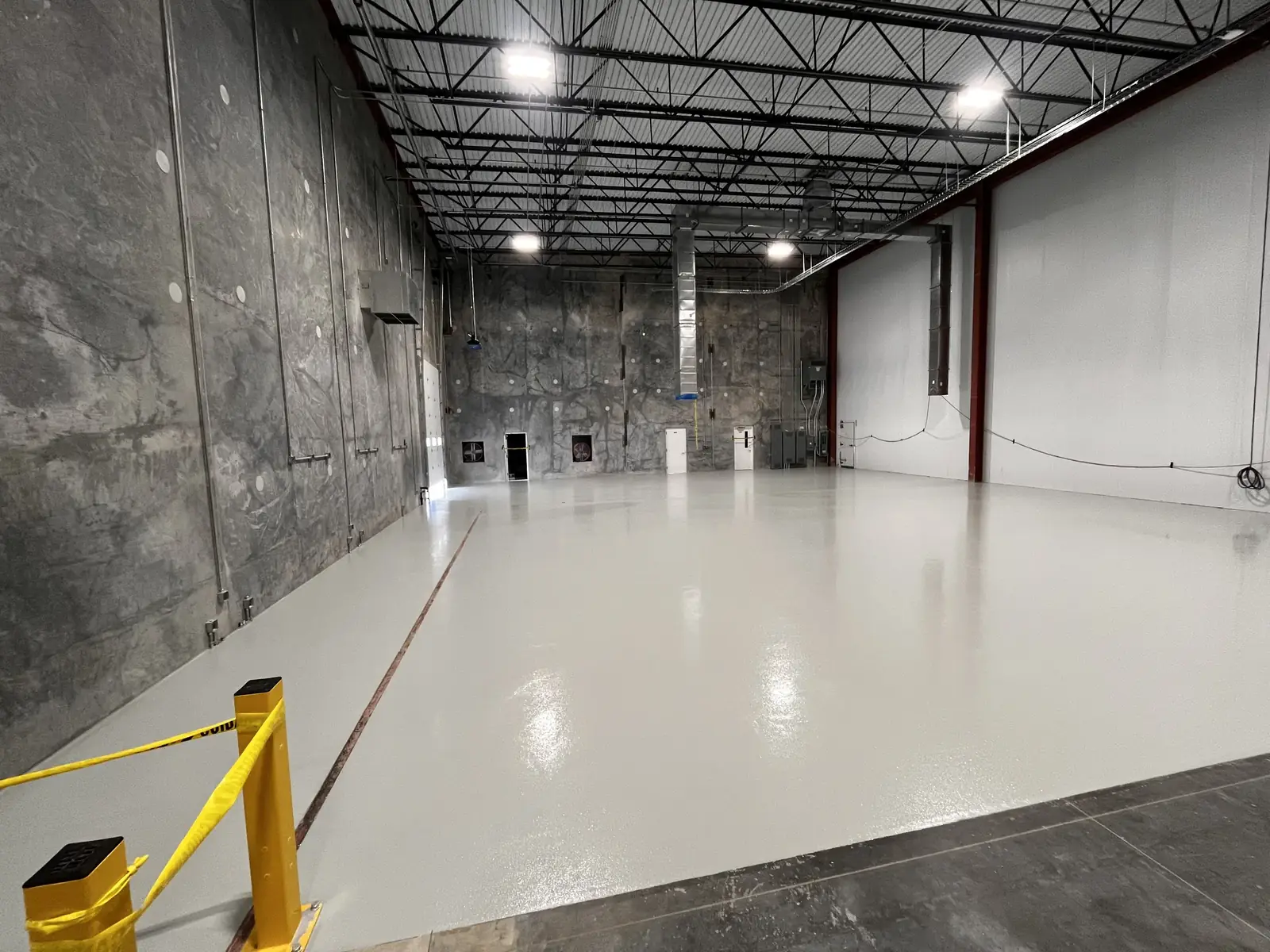 Manufacturing bay with light gray high-build epoxy floor and safety bollards