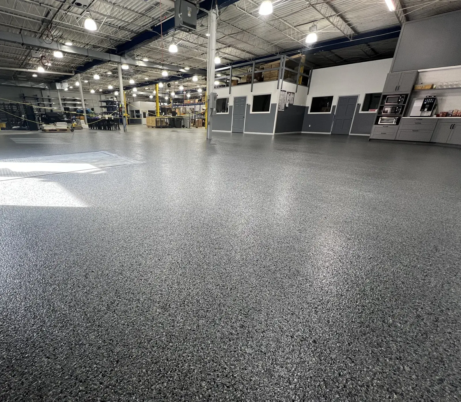 Decorative flake epoxy floor across a working manufacturing shop